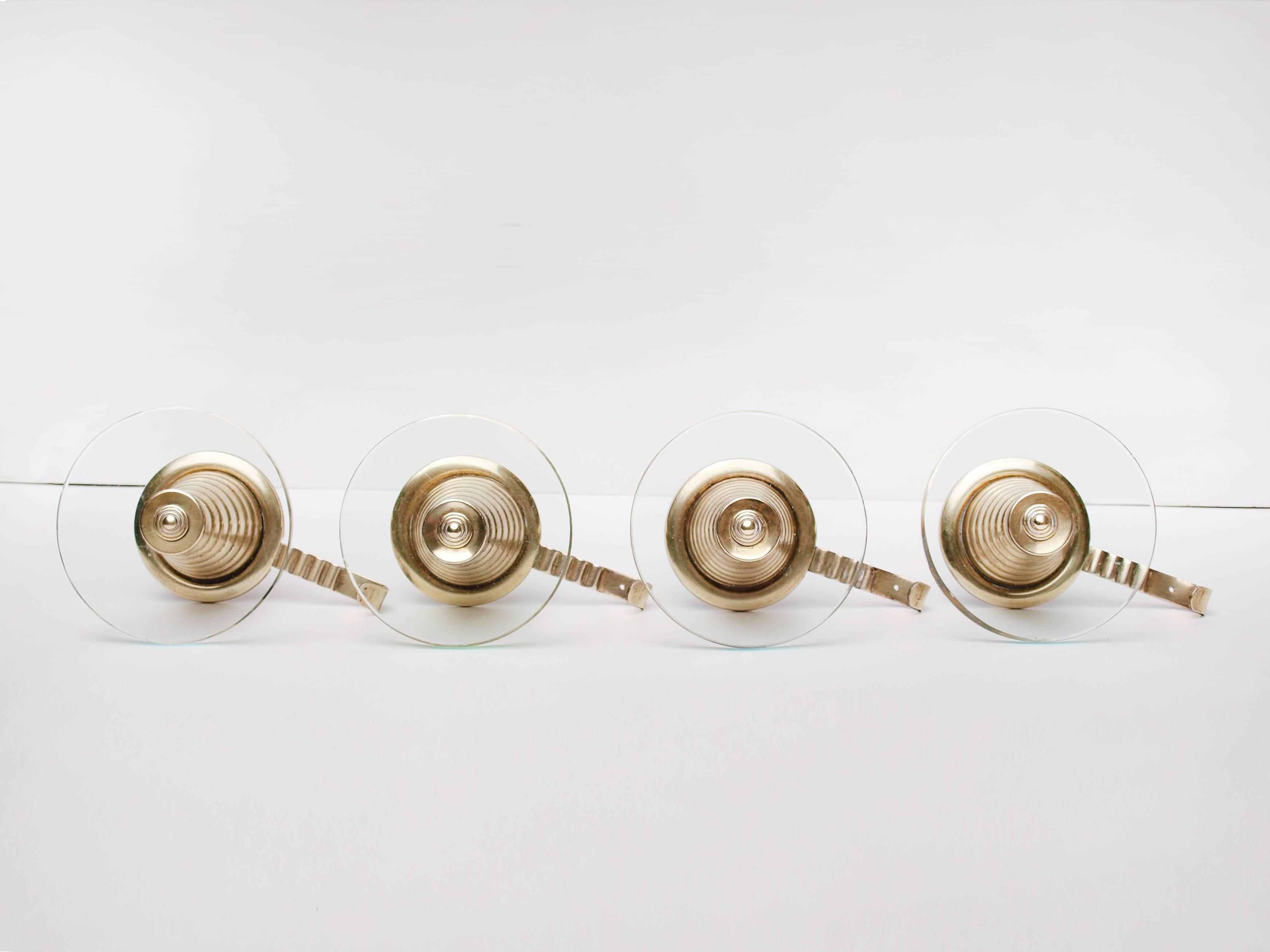 A set of four cone shaped Italian brass and glass wall-mounted coat hooks designed, circa 1950, with ornamental circular glass discs and brass concentric detailing.