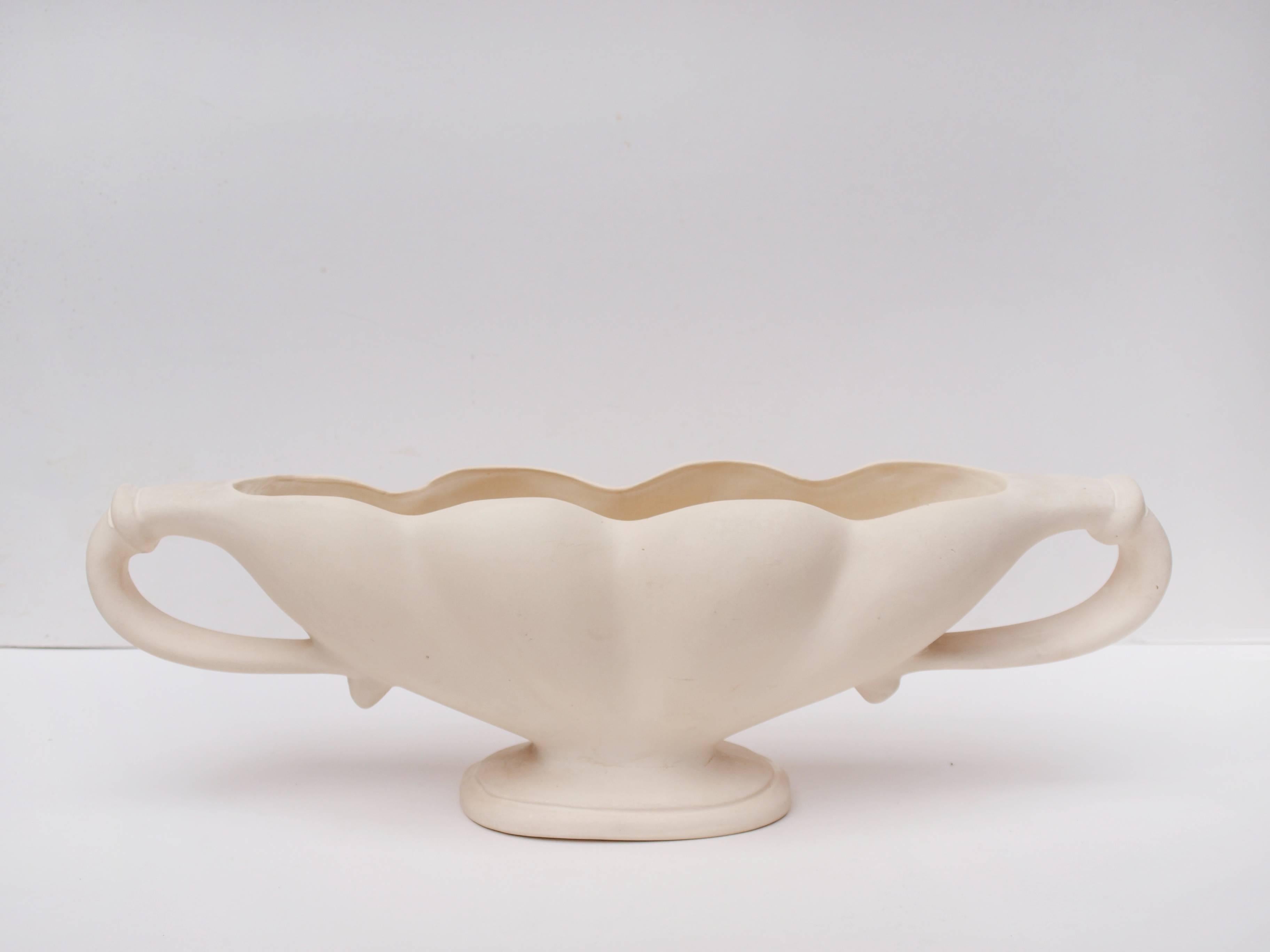 A striking 1930s ivory glazed twin-handled mantel vase designed by the influential florist Constance Spry for Fulham Pottery. The exterior of the vase is matt, with a glazed interior. Stamped Fulham Pottery to the base.

With it's undulating form,