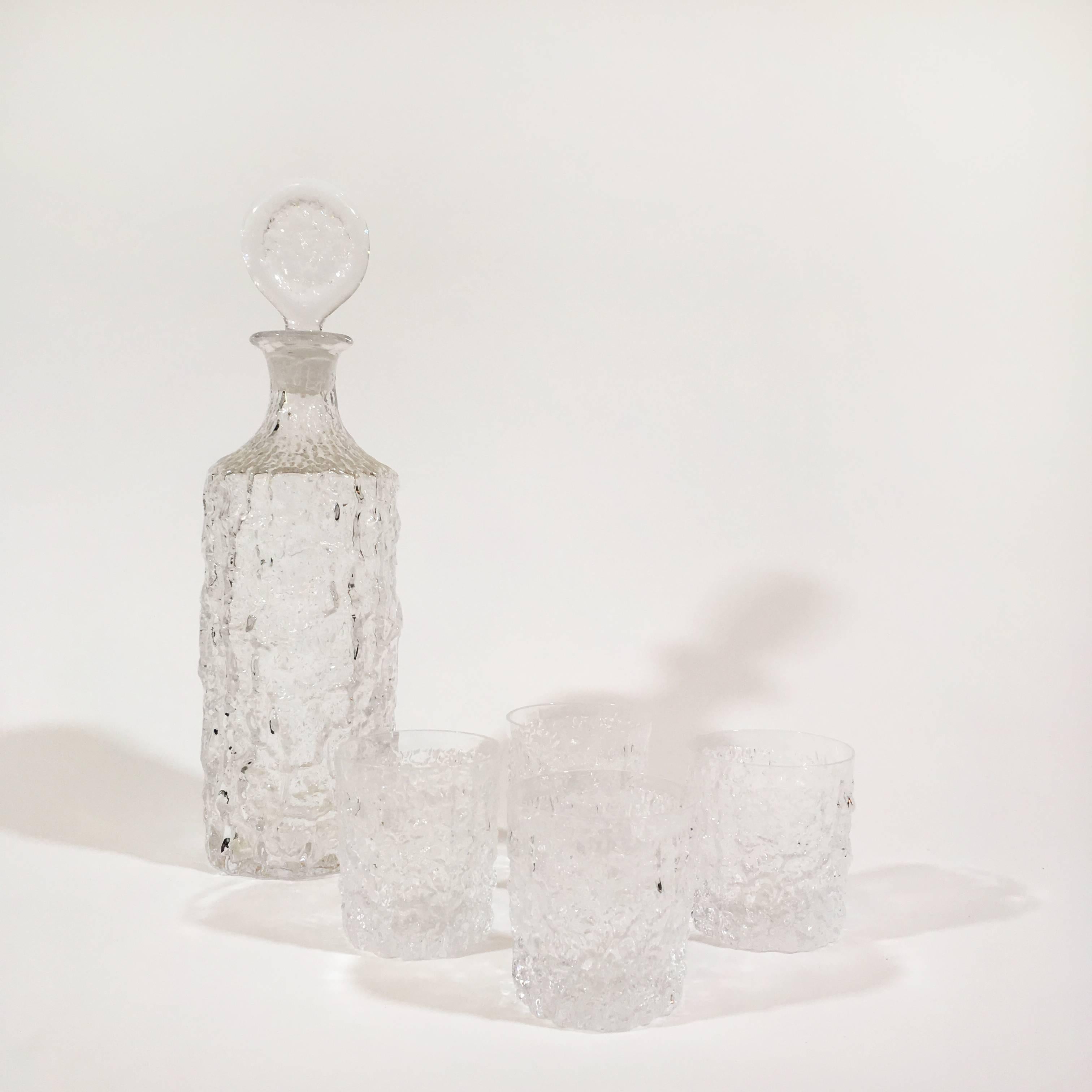 A Whitefriars glacier crystal glass decanter designed in 1972 by Geoffrey Baxter with four whisky glasses. A Classic design which has stood the test of time.
Measure: Decanter depth 3.75; width 3.75; height 13 inches
Glasses 2.75 D x H 3 inches.