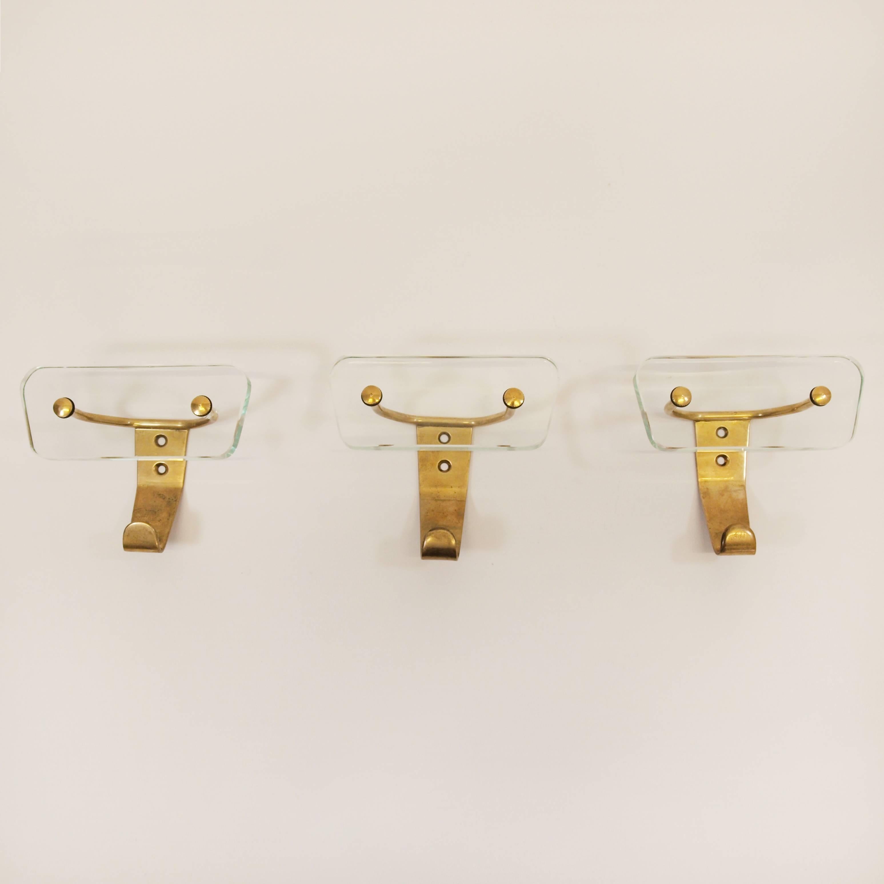 A beautiful trio of 1950s brass and glass wall hooks attributed to Fontana Arte.
Constructed from highly engineered brass in a dramatic bull Horn form, the design is offset by the original thick 6mm cut-glass in a trapezium shape.
 