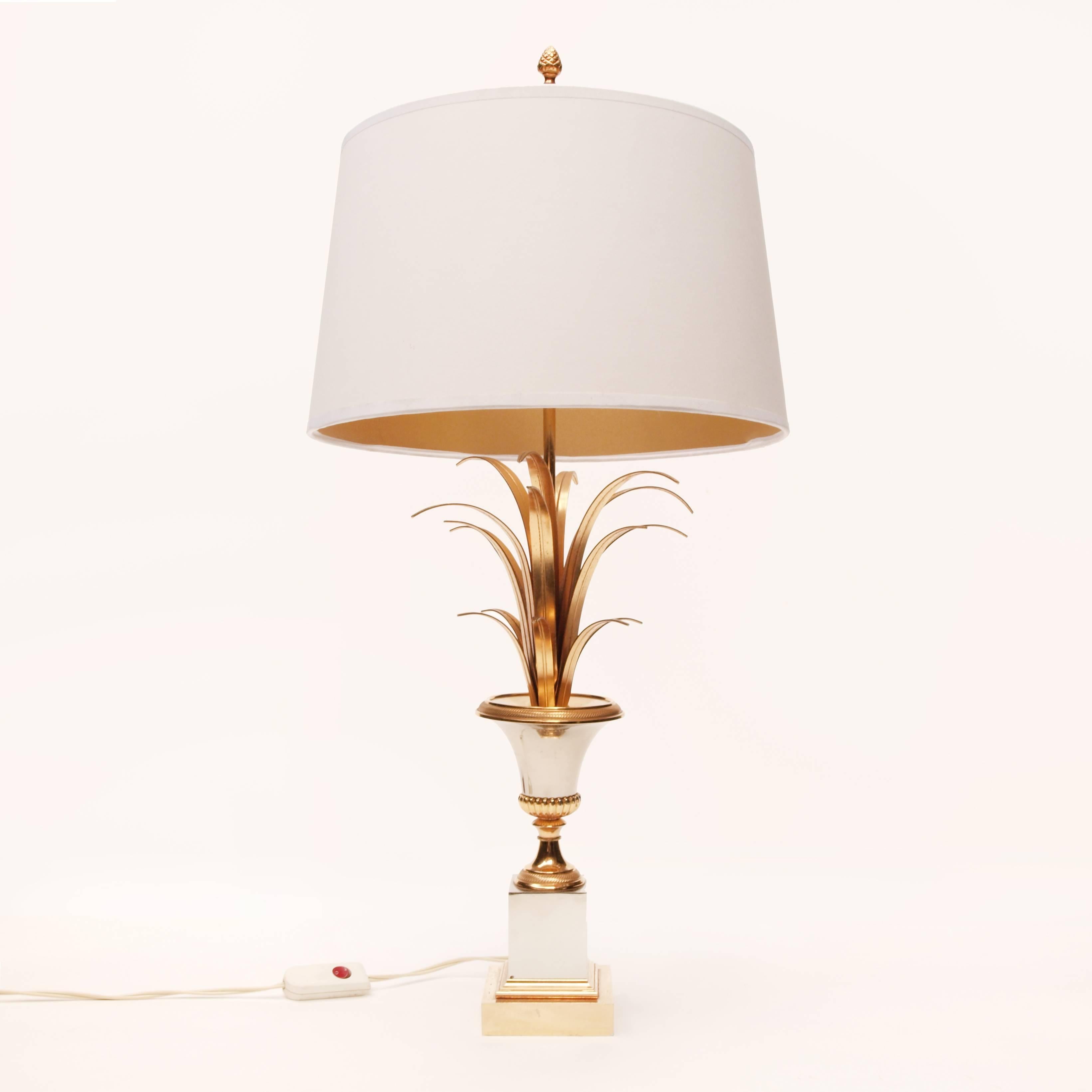 A beautiful Maison Charles style pineapple lamp. Typically neoclassical in style this lamp is finished in silver and brass, appointed with an acorn finial and gold lined shade, which all sits neatly on a polished sharp square base.