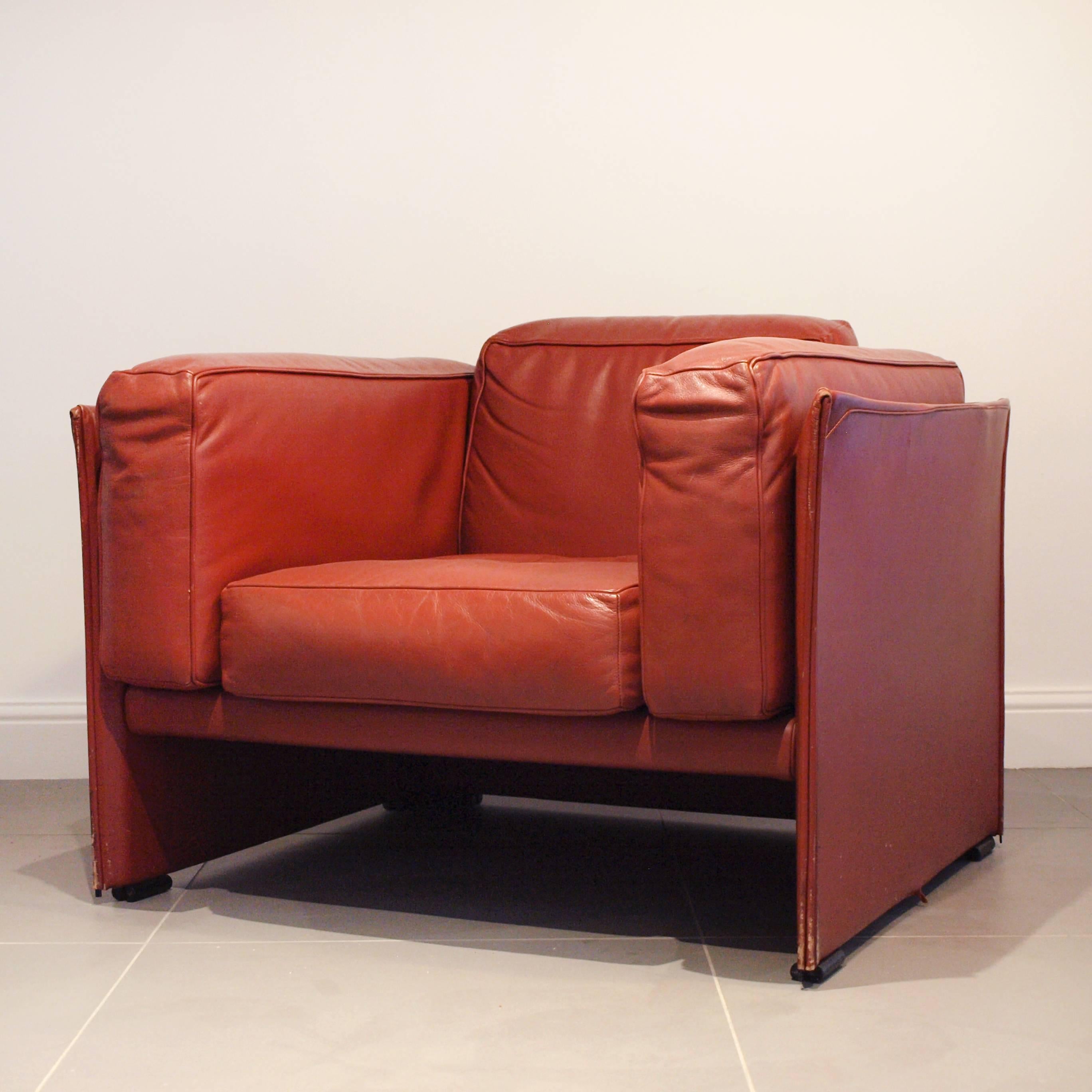 A red leather Cassina 405 Duc armchair on chrome feet, designed by Mario Bellini. At the heart of the chair are four large red leather square cushions, these are encased in a cube-like outer body, with a slightly scalloped edge towards the top