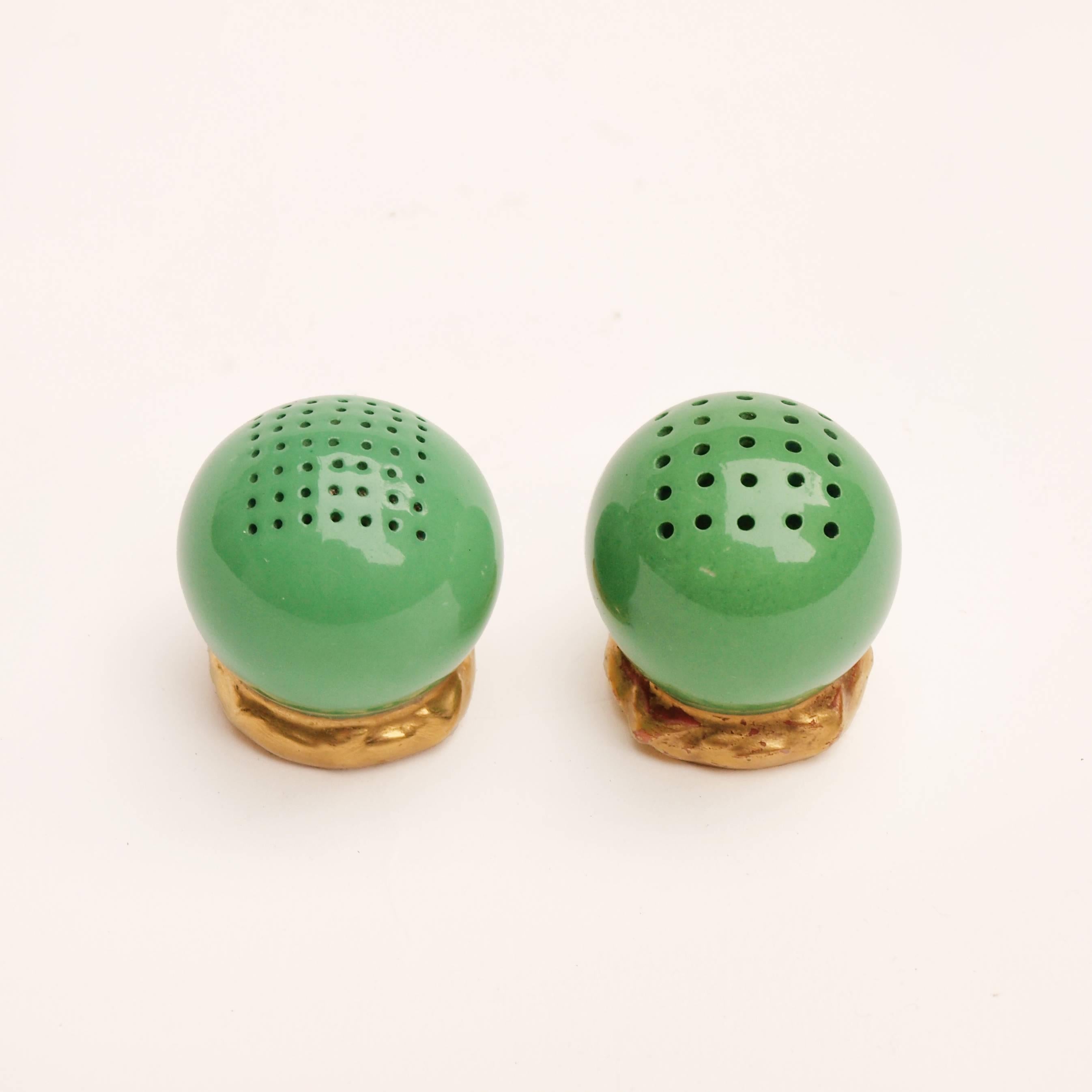 A pair of small spherical green ceramic and gold gilt salt and pepper shakers made by Royal Worcester. Signed and dated 1909 to their base.