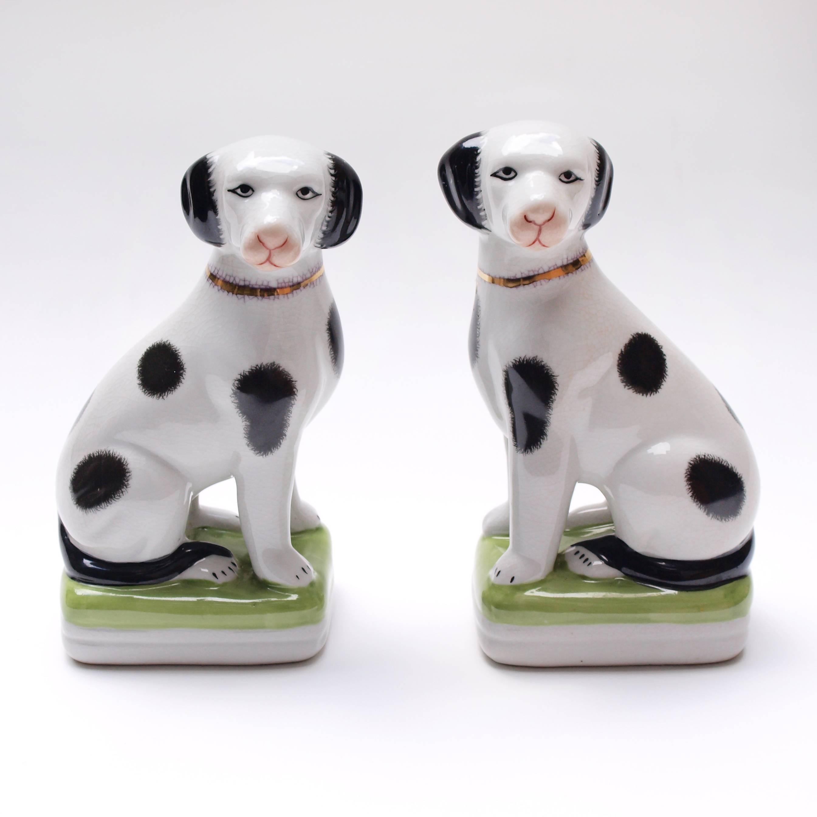 A pair of 1950s painted mantle dog ornaments with hand painted features and a gold gilt collar. These ornaments are a 20th century take on the Victorian Staffordshire pottery hearth spaniels. 