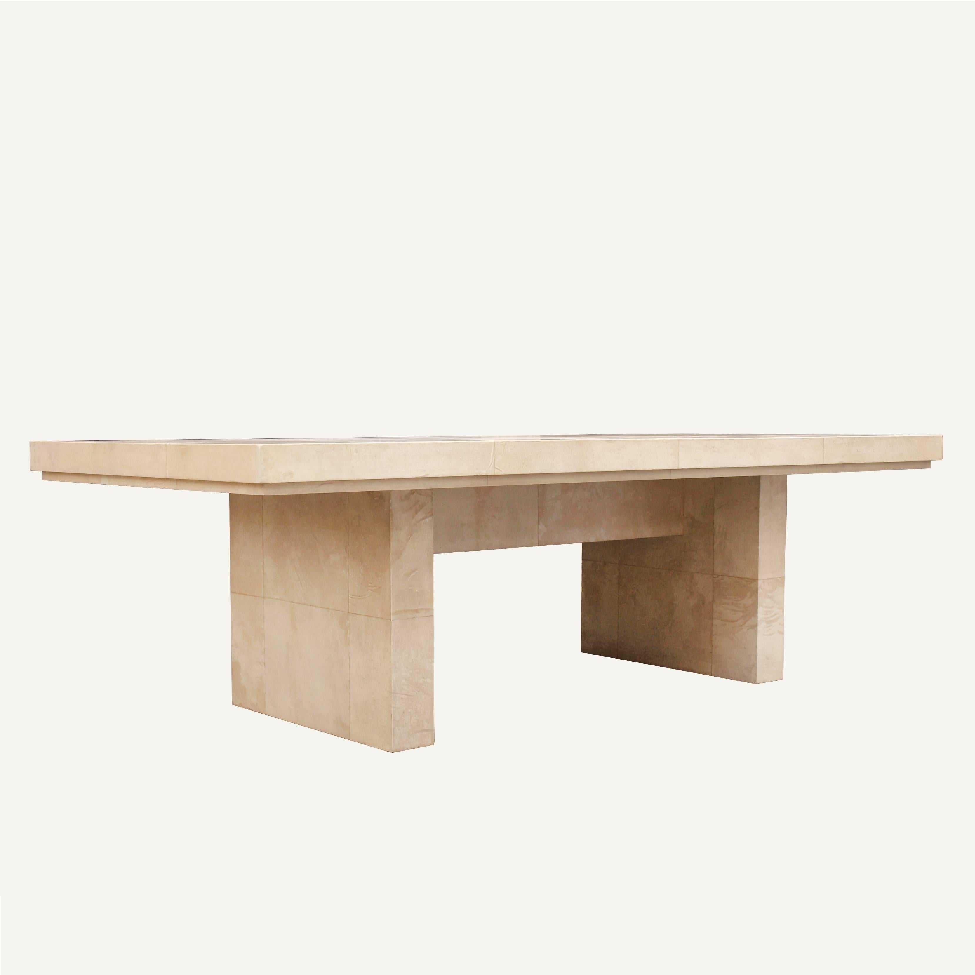 A large modernist dining table covered in natural beige goatskin parchment. The parchment has a straight cut rectangular inlay pattern and smooth matte lacquer finish. Simple and clean lined this table can also be used as a statement piece desk.