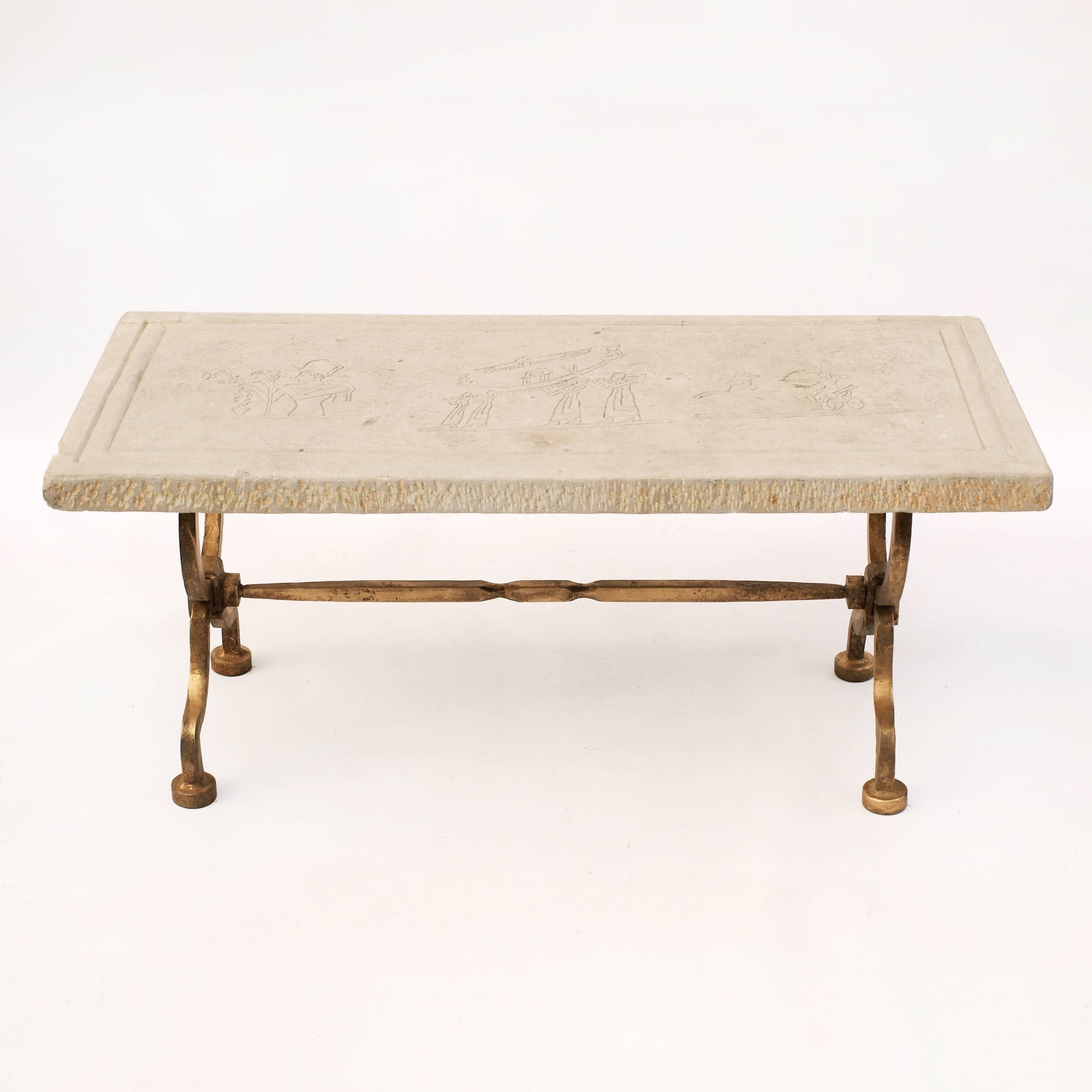 A cast iron base with a gold gilt effect on the surface and repeated decorative motifs following the shape of the legs, supports a limestone top with ancient Egypt inspired carved imagery.
The table dates from the early 1940's and the carvings on
