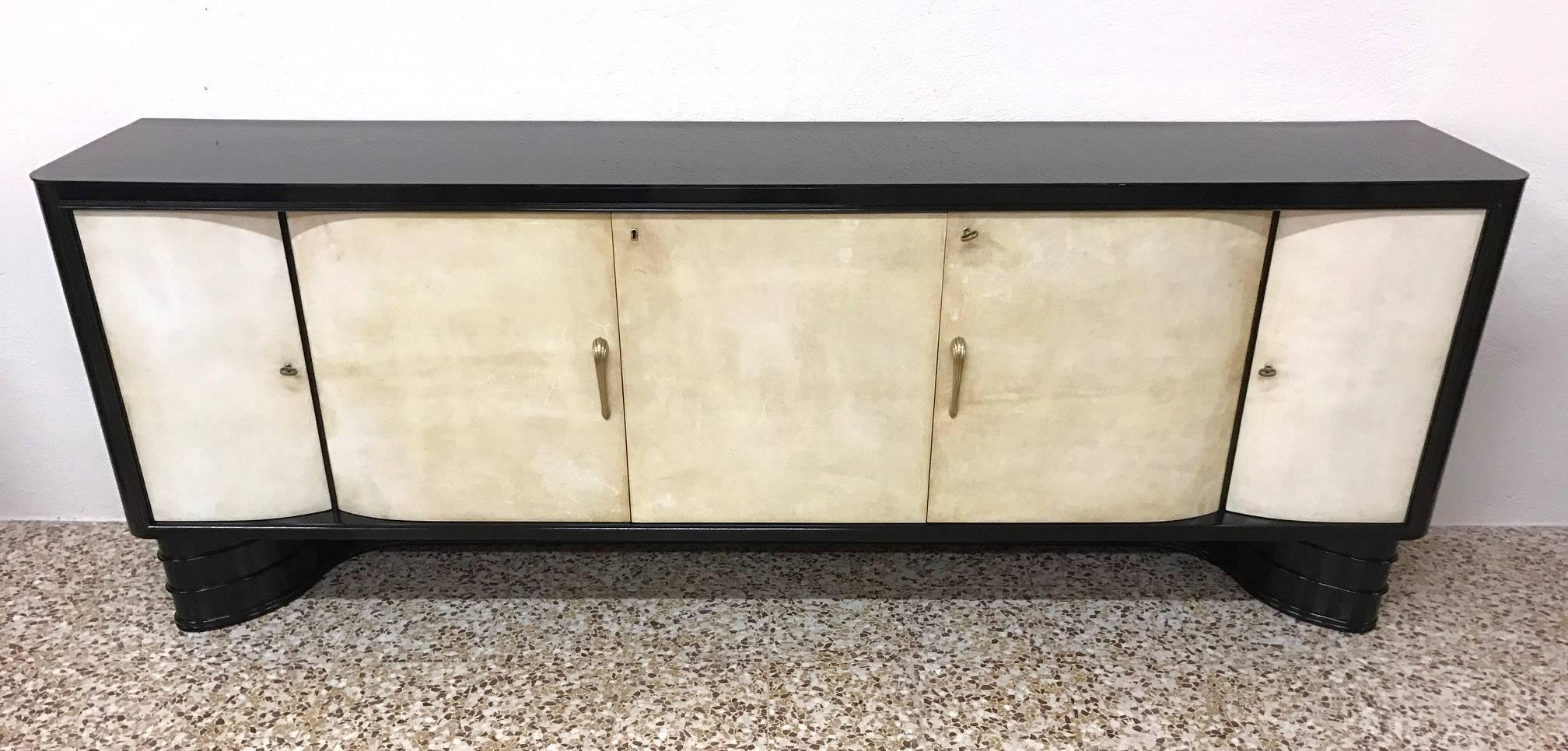 A great 1940s sideboard with parchment doors, black lacquered structure, shelves and drawers on the inside and a black glass on the top. On one door there is the brand ‘Esposizione permanente mobili Cantù’.
The sideboard is in perfect