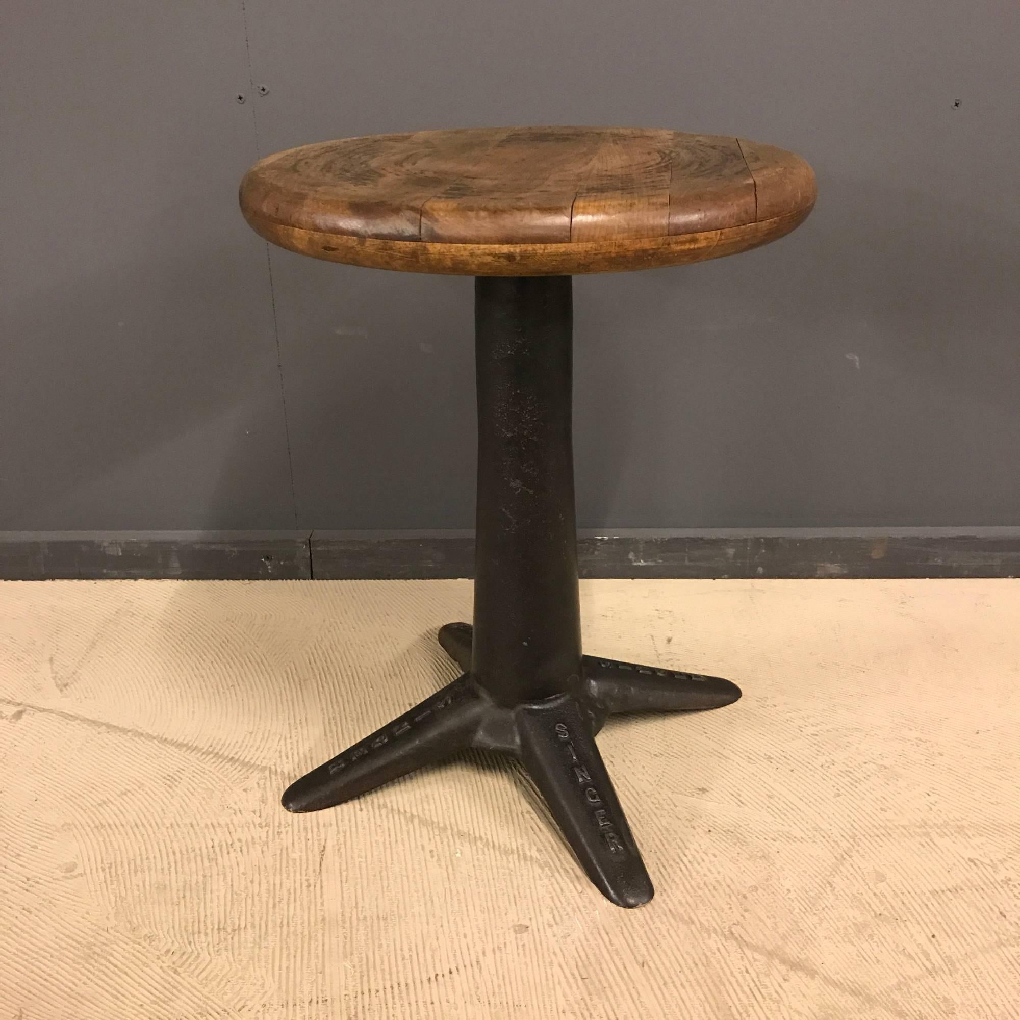 Industrial workshop stool by Singer. Heavy cast iron base with solid oak top. Made in France during the 1930s. This stool remains in good condition.