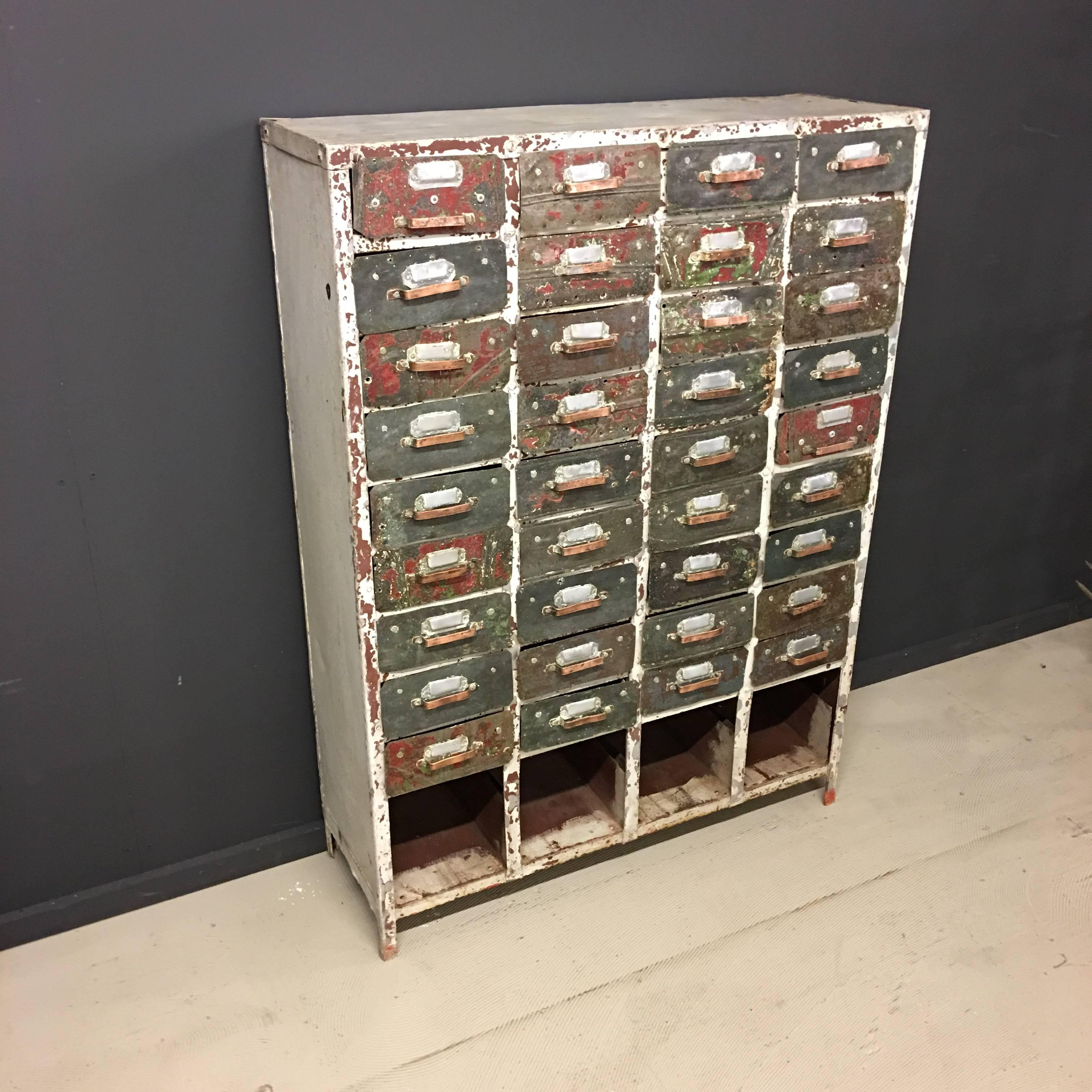 This French Industrial drawer cabinet was made during or shortly after the war. Made by hand, using old, left over, materials, all 36 drawers are made from oil cans and the handles are made from copper. Each drawer is unique and has label holders.