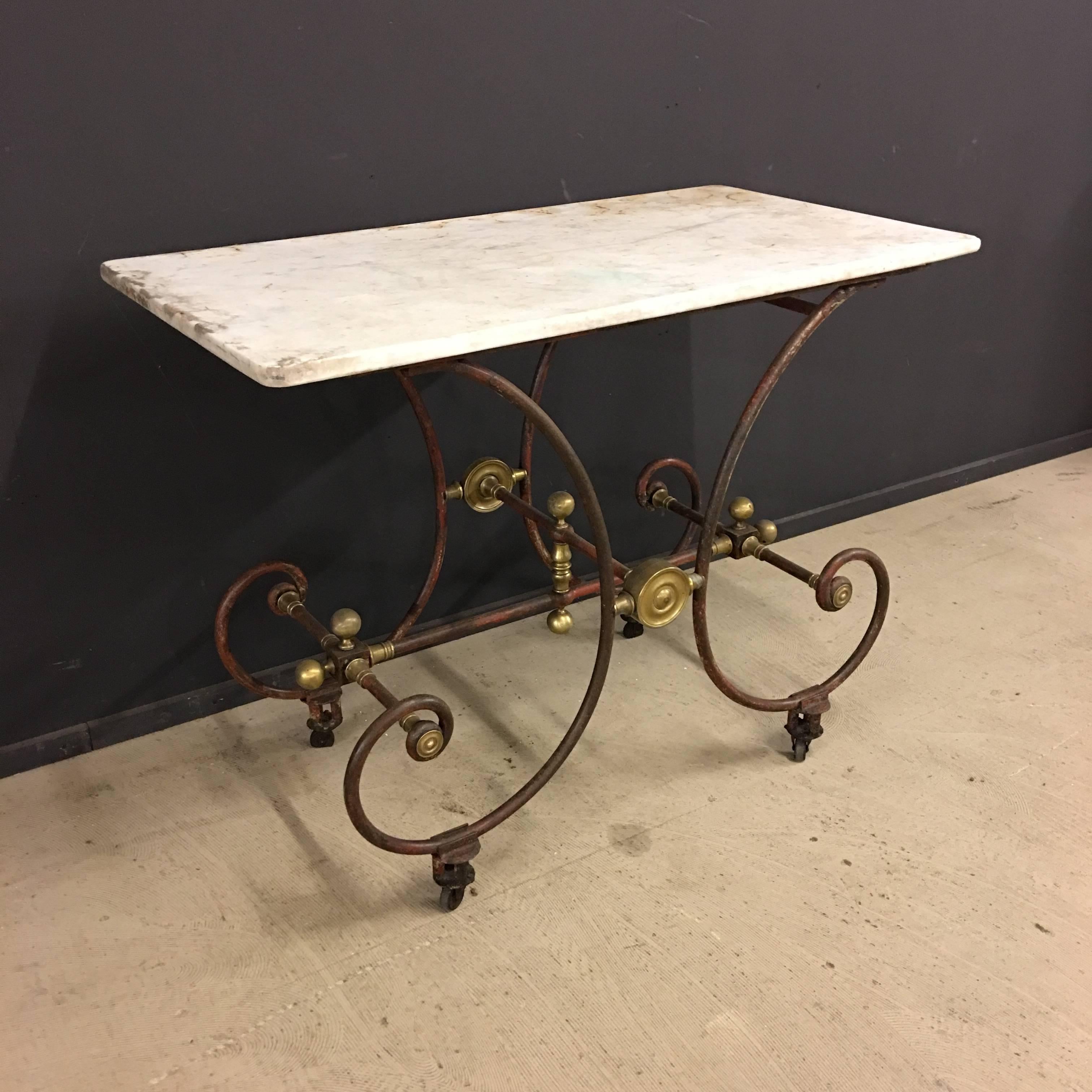 This antique French butchers table was manufactured by J. Mareschal, Paris, in the 19th century. It features a cast iron and wrought iron base with brass element and white marble table top with nice patina.