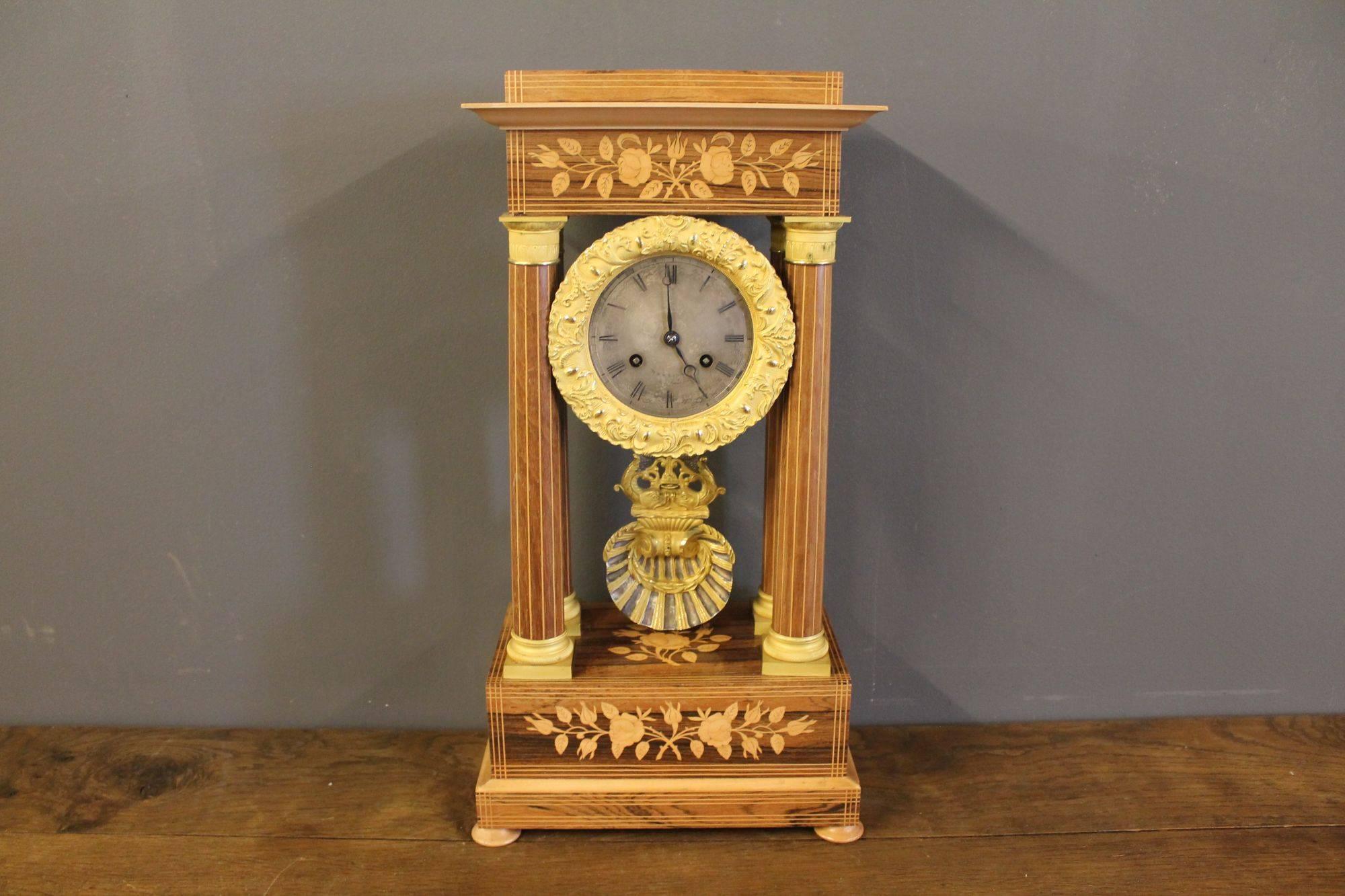 Beautiful ormolu clock in Empire style, protected under a glass dome and supported by a walnut foot. Both the body and the foot are splendidly worked with rosewood inlay. Made in France, circa 1850s.