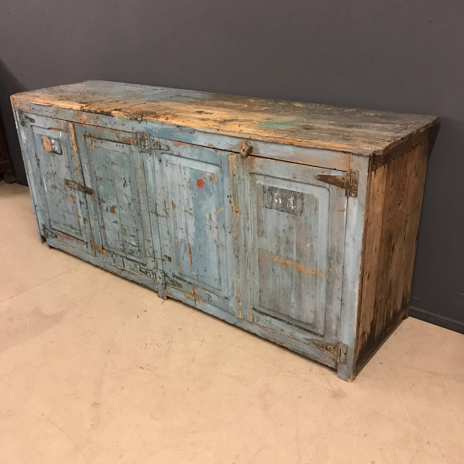 This Industrial workshop cabinet was used as a workbench and for storage in a factory in France. It was made in France during the early 20th century. It has big wrought iron hinges and multiple layers of old paint. Has been cleaned and can now be
