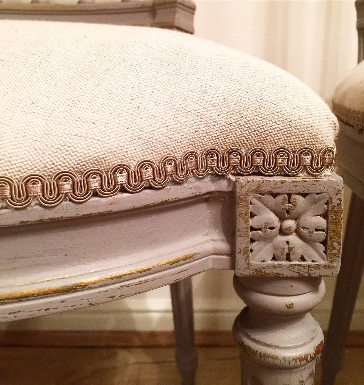 A fantastic pair of 19th century French chairs recently re upholstered in a neutral linen fabric with latter paint showing the original gold paint showing through.