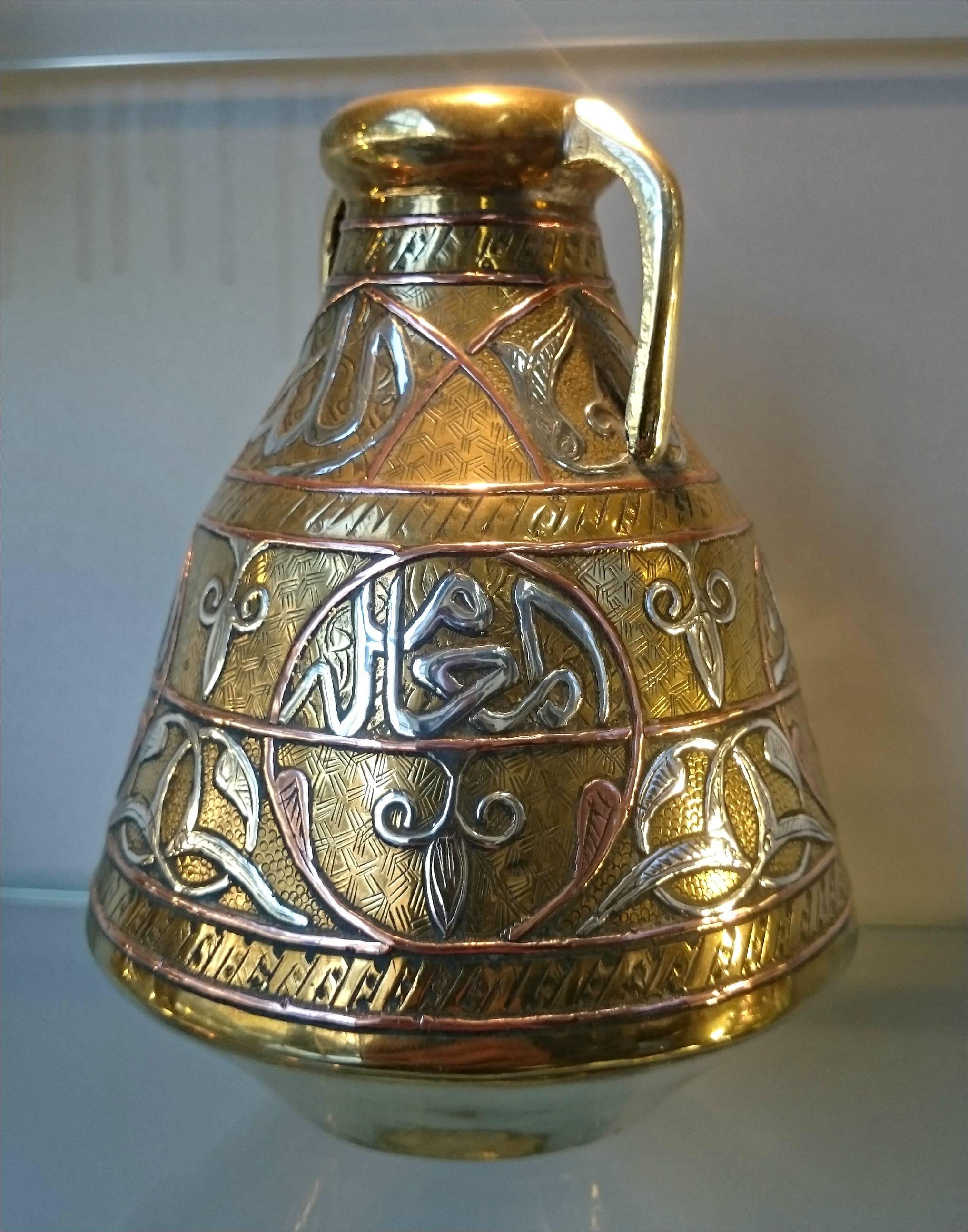 An early 20th century Islamic silver and copper inlay on brass two handles vase.
The inlay decorations consist of typical Arabic geometric motifs, and Islamic religious writings.
possibly made in Egypt, as Cairo-wear.
 