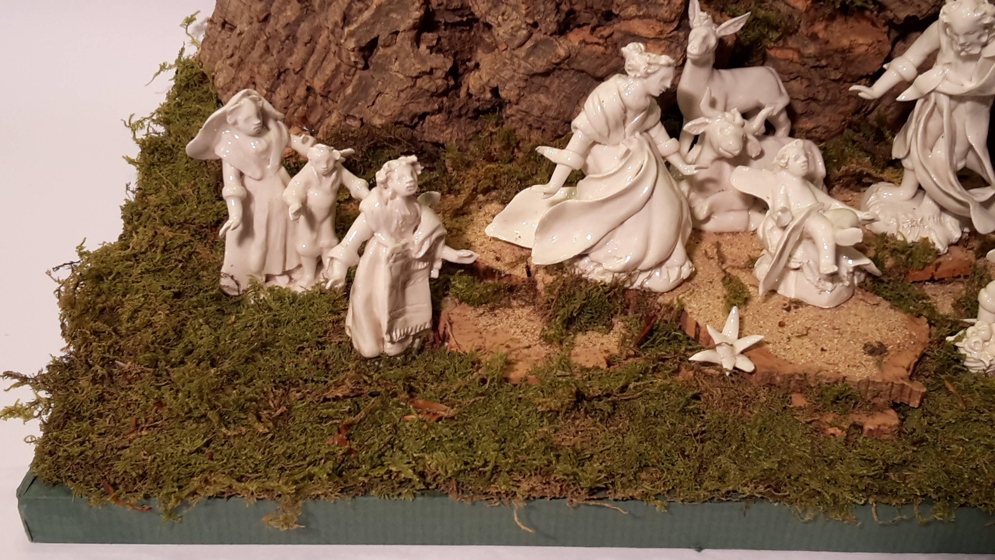 Contemporary nativity scene, handmade according to the Neapolitan tradition from the Baroque period, the use of the white porcelain, the mountain on which the angels flying, is in carved cork. The base is made of wood painted green with moss.