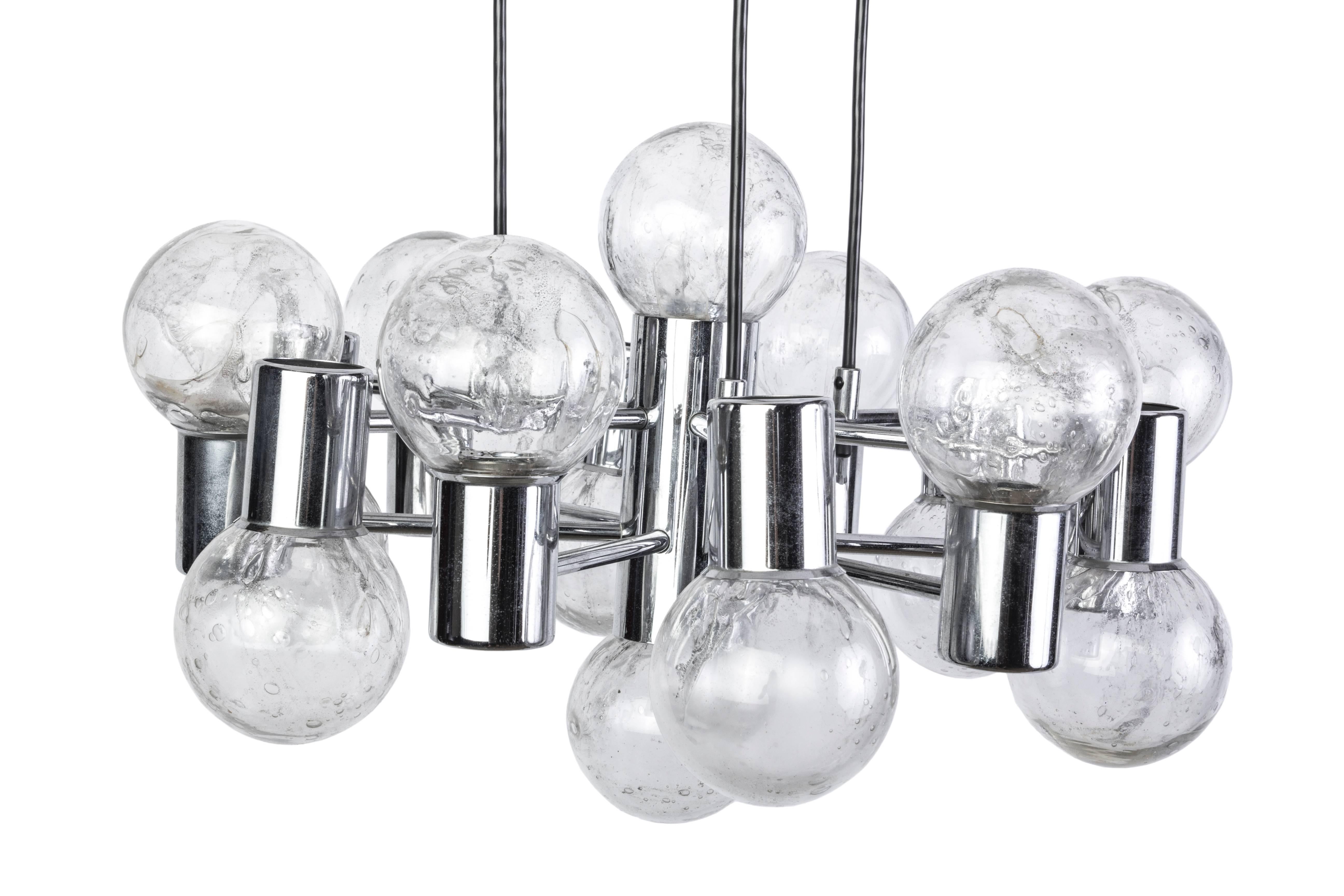 This stunning Mid-Century Modernist chandelier was designed by Doria. It features an orbital form design on a chrome frame with bubble textured transparent glass shades.
