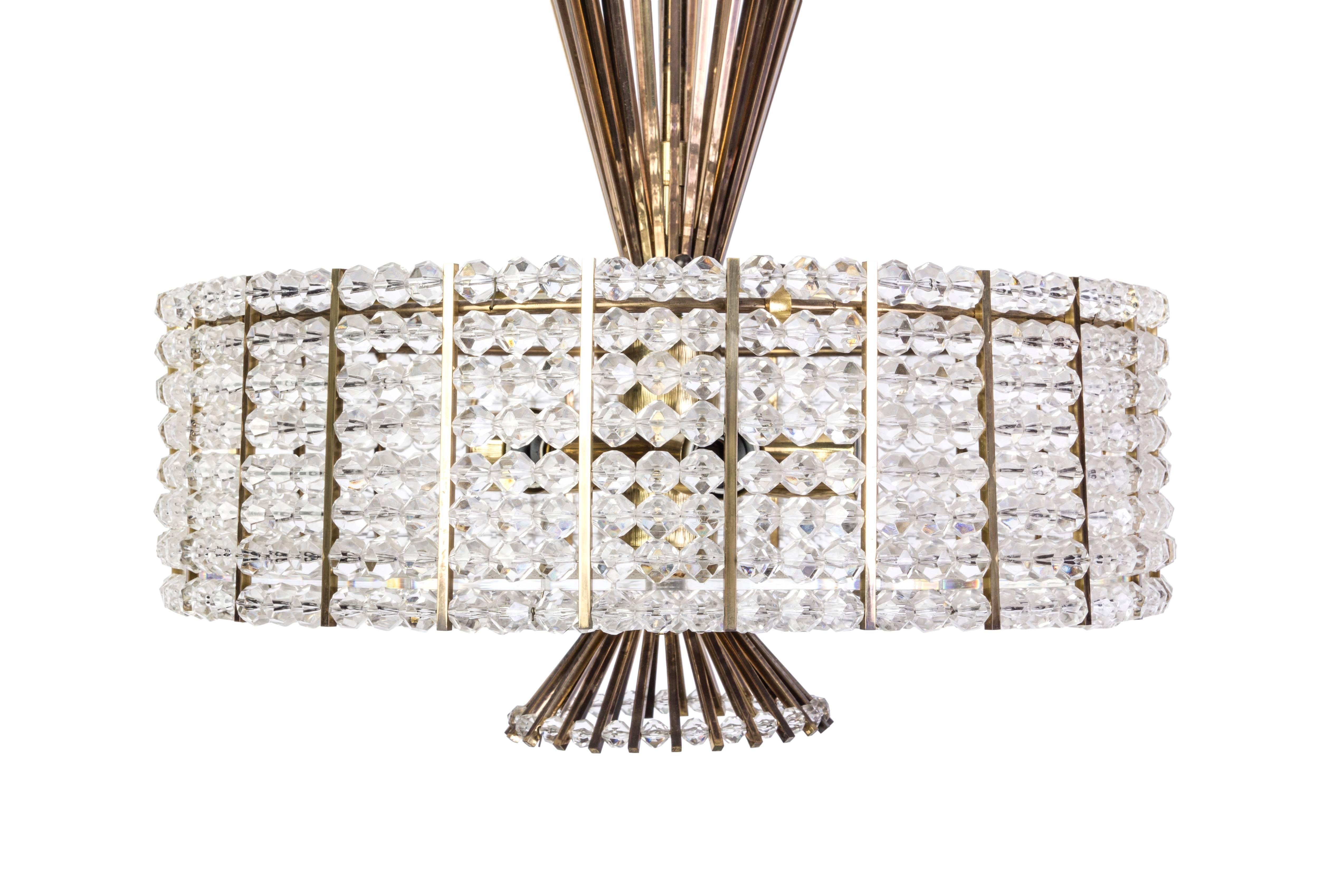 This sensational Mid-Century Modernist chandelier was designed by Emil Stejnar for Rupert Nikoll. It features a circular drum of Lucite and acrylic chain detailing connected to a brass base with conical form lines protruding from the top and bottom