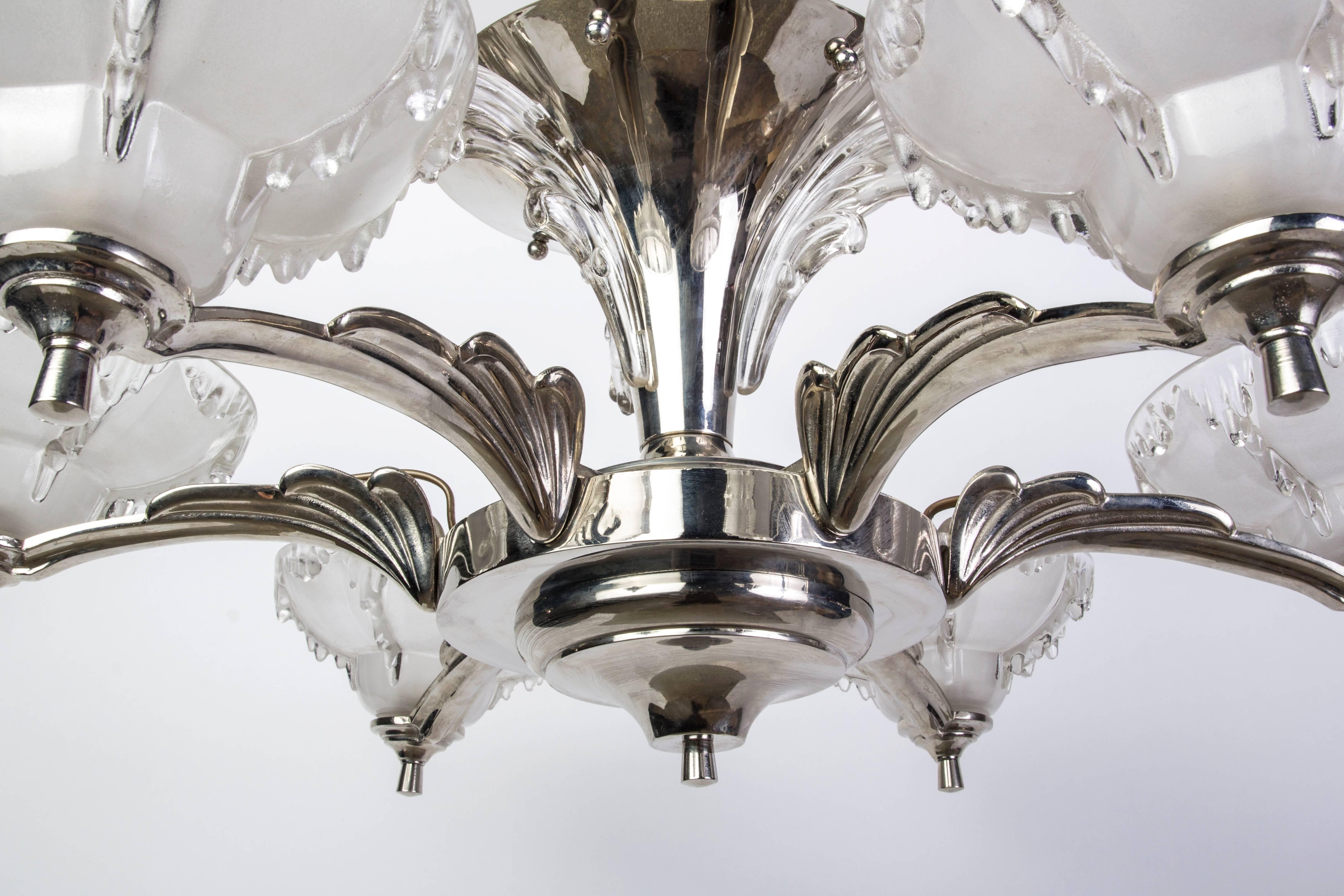 This impressive 1930s French Art Deco chandelier was designed and signed by Petitot. The frame has (three) trumpet cascading tiers that is composed of nickel-plated copper. The (six) lights are encased in relief frosted glass with icicle detailing.
