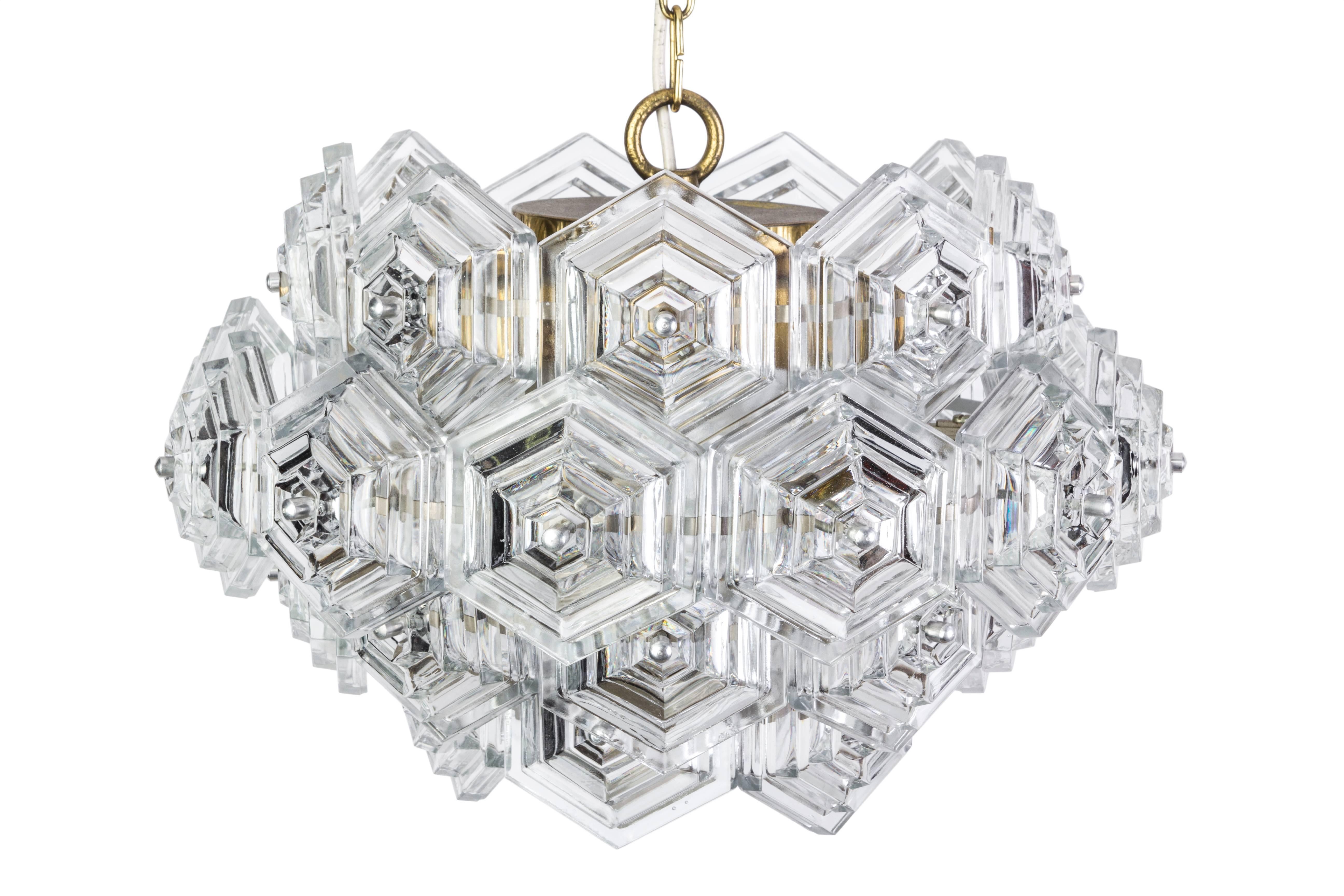 This beautiful Mid-Century Modernist chandelier features a four tiers honey comb design in stylized hexagonal form of clear crystals attached to a brass chain. It is in excellent condition and has been newly rewired.