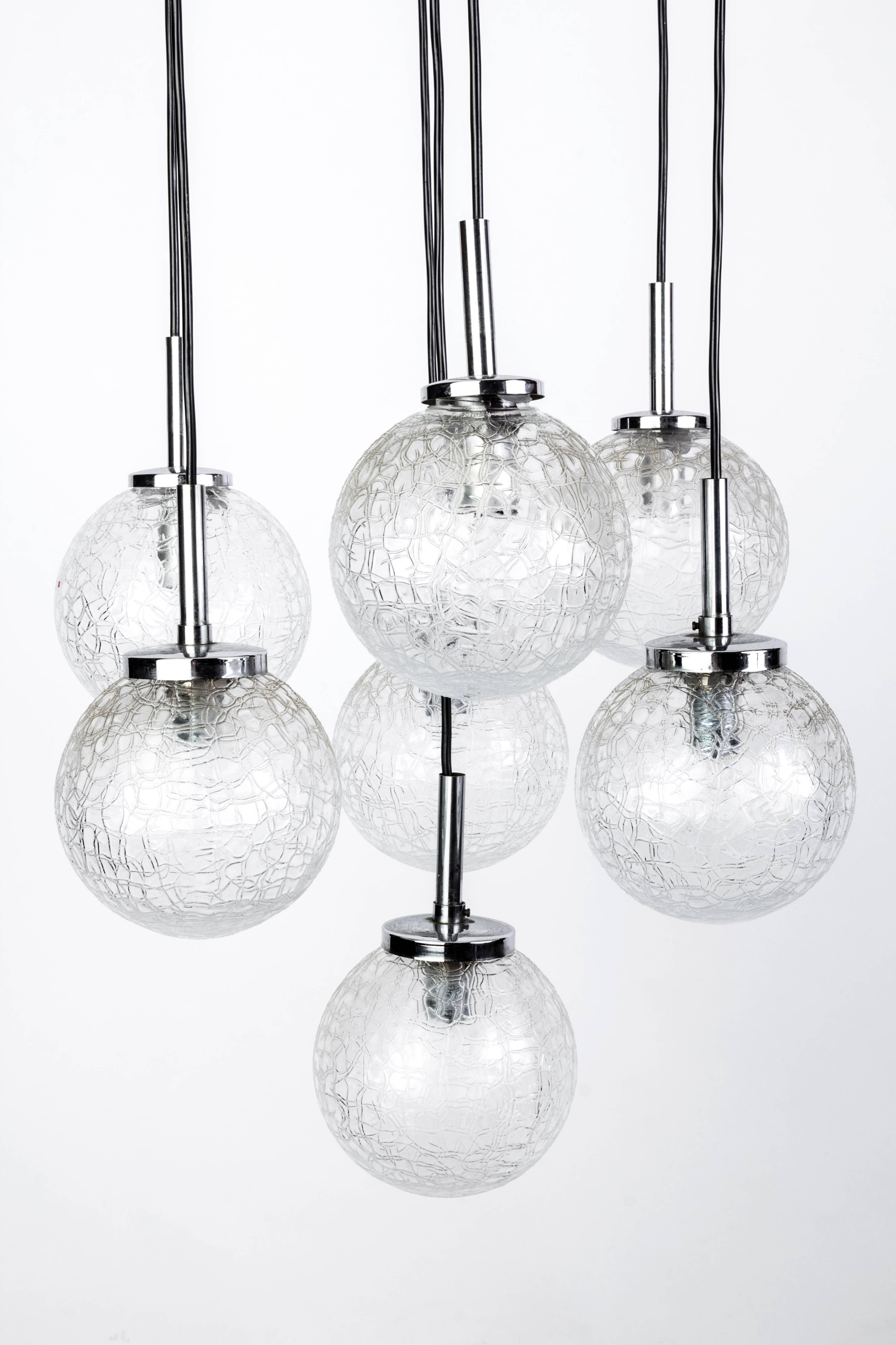This stunning Mid-Century Modernist chandelier by Doria features seven etched glass ball shades descending from a star form black lacquered base with chrome detailing.
                             