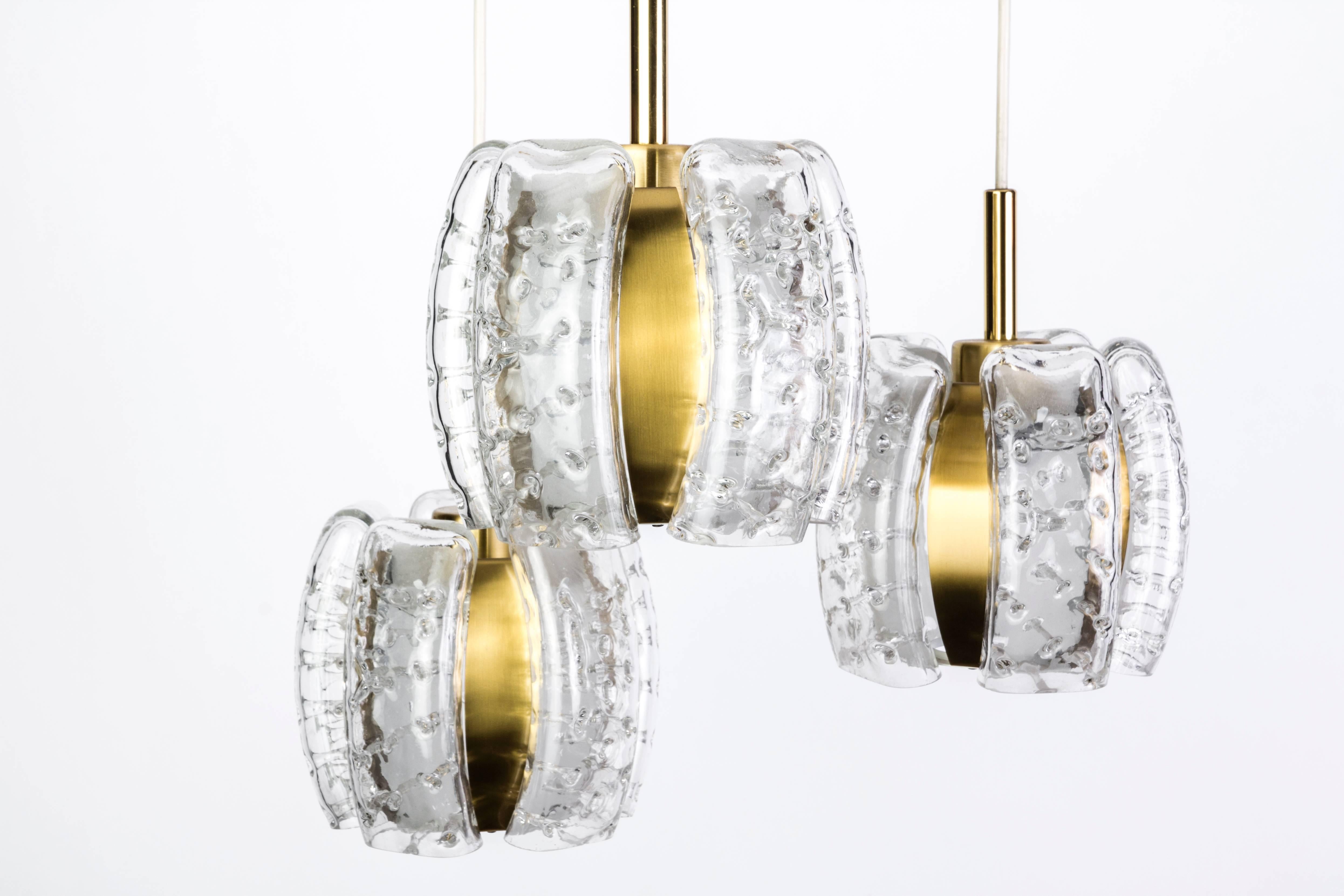This stunning German chandelier was designed by Doria. It features cream enamel and brass detailed frame cascading into three octagonal form shades with textured bubble glass panels and brass accents.

Made in Germany, circa 1970.