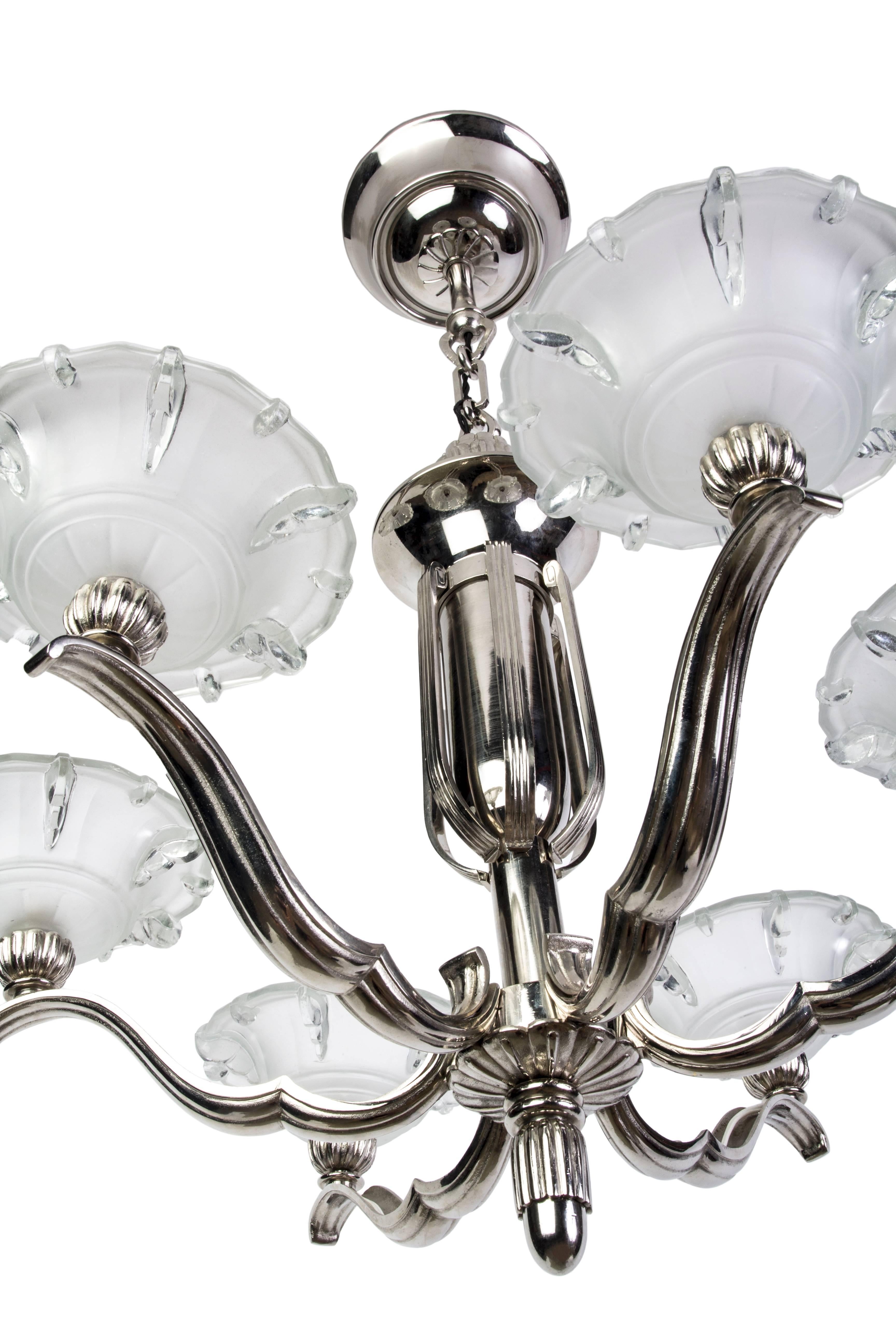 This exceptional Art Deco chandelier was designed by Petitot. It features a nickel-plated frame with six stylized floral frosted glass shades. It is in excellent condition and has been newly rewired.