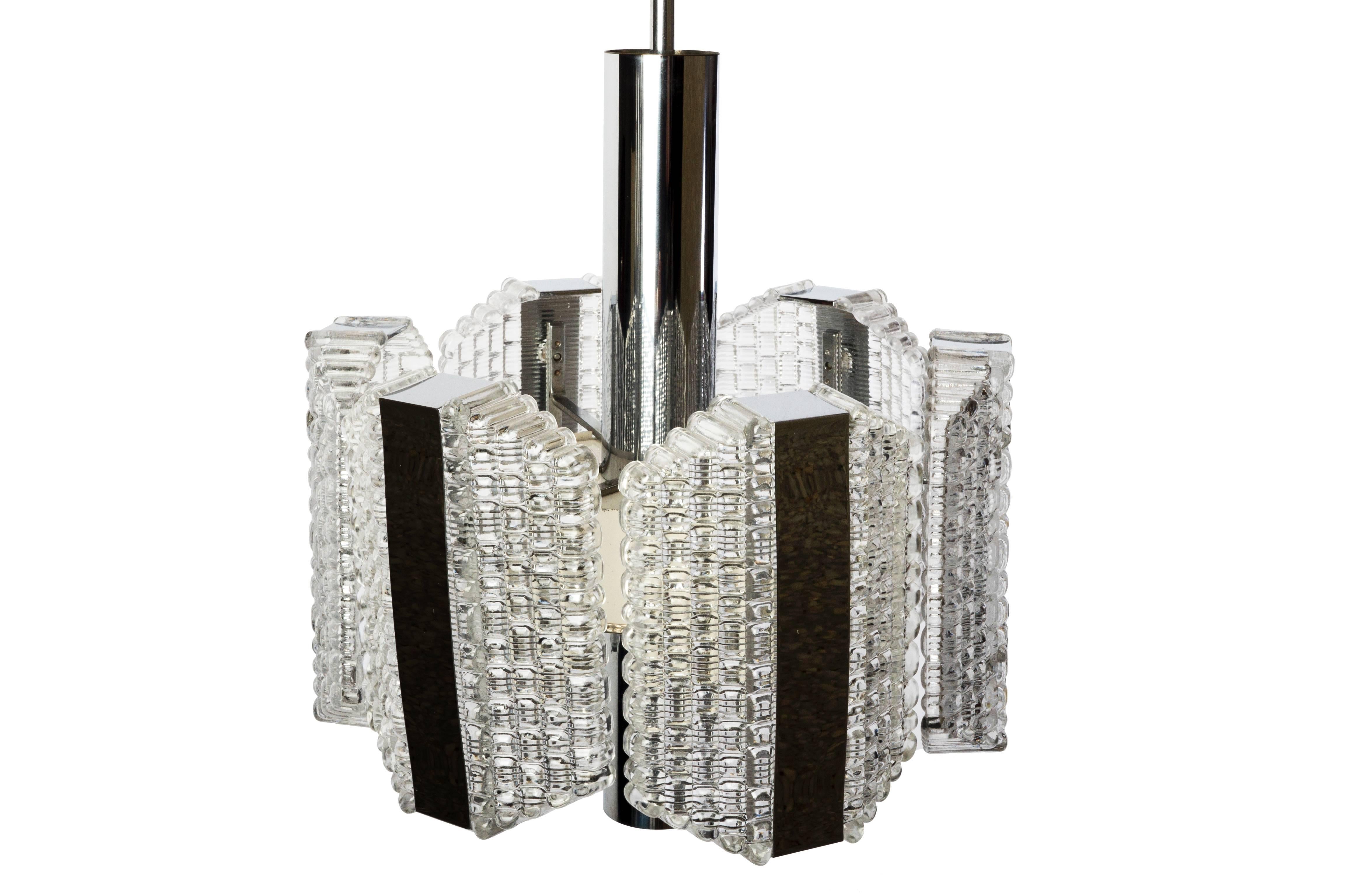 This sensational Mid-Century Modernist chandelier was designed by Kaiser Leuchten. It features a hexagonal shape, textured relief glass design and chrome banding detail. It has been completely rewired and is in excellent condition.