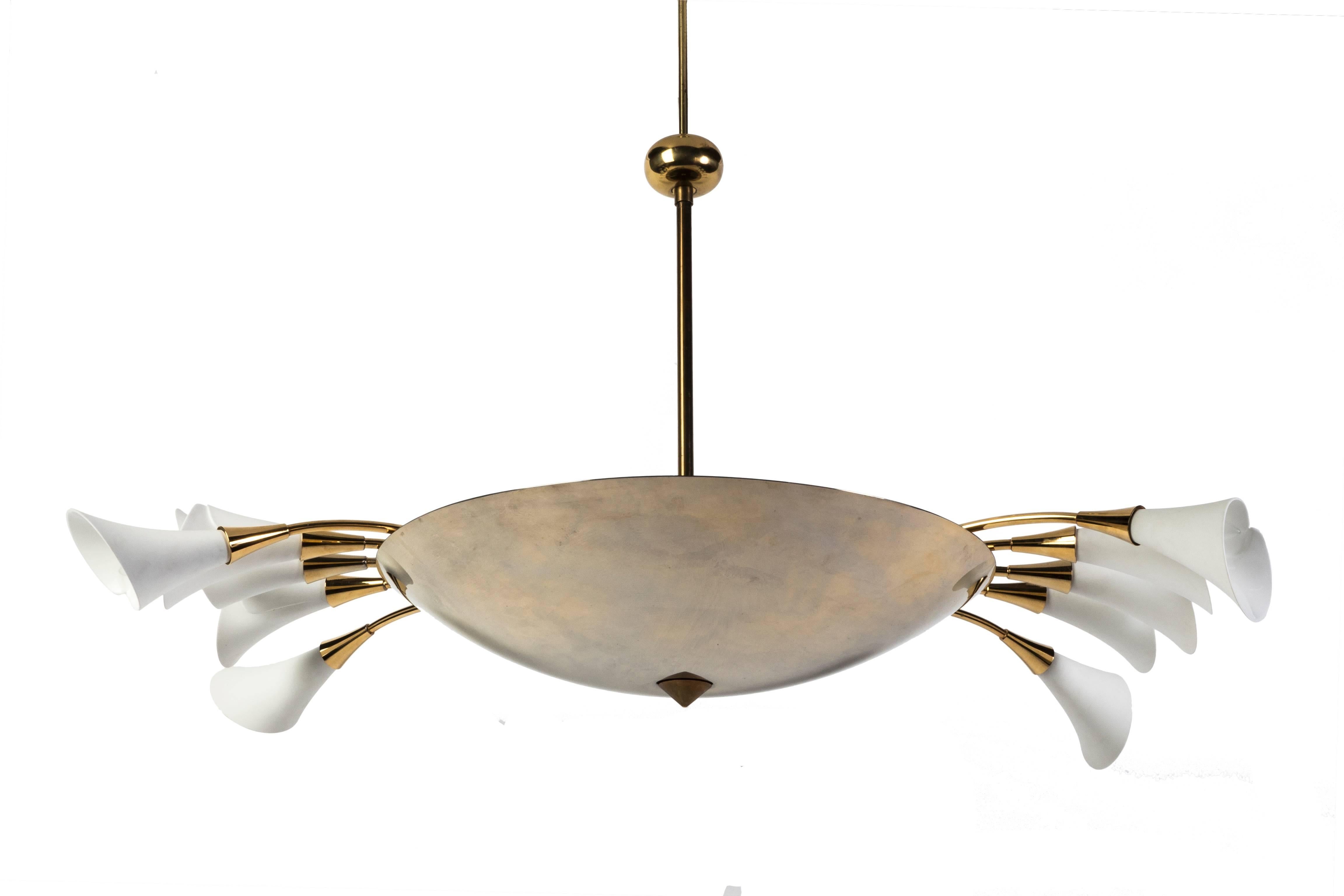 This stunning polished brass Italian chandelier features a reflective brass center bowl from which extends ten-arms with porcelain shades fashioned after calla lilies. This piece was made in the 1950s. Only two of these chandeliers exist worldwide.