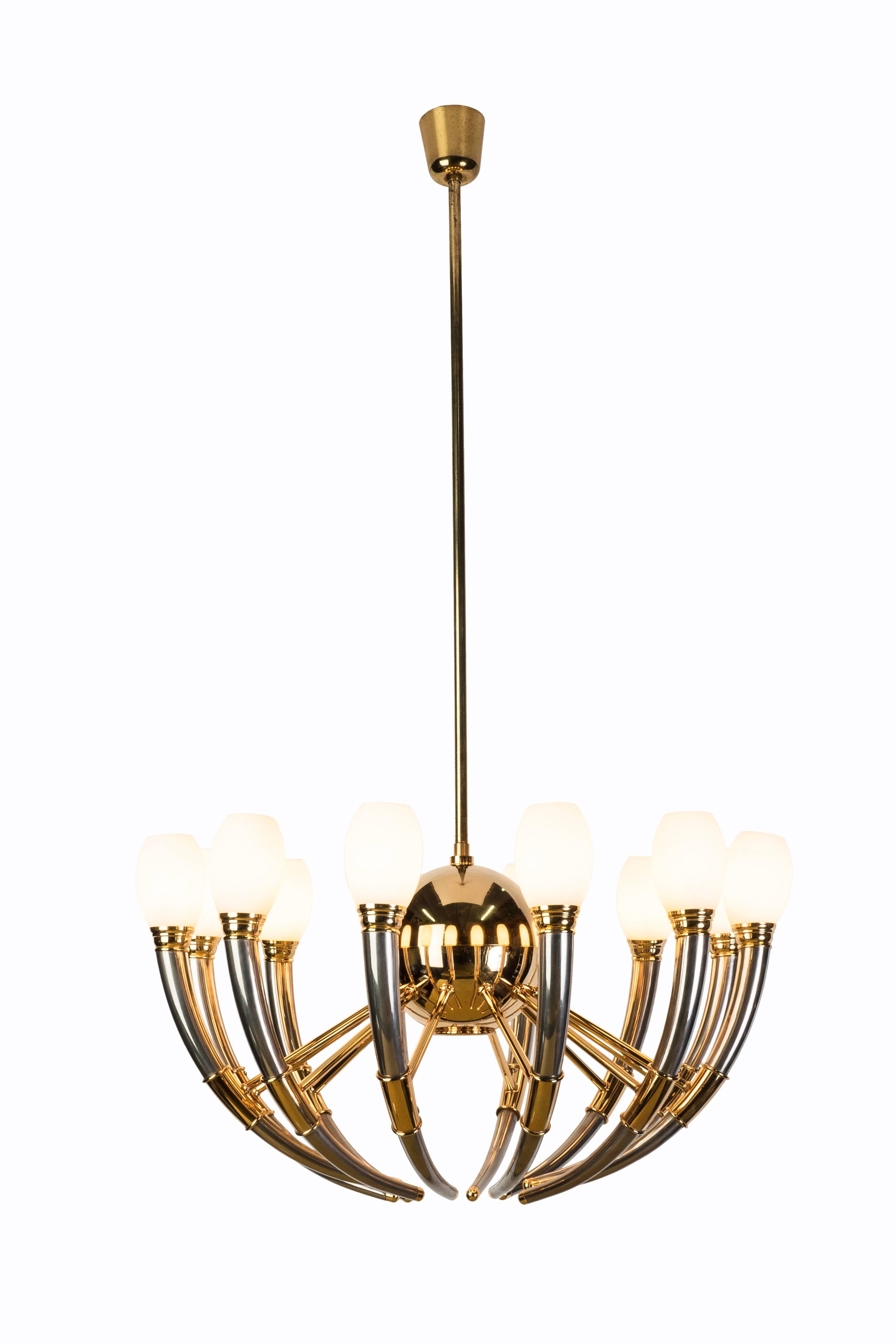 This gorgeous thirteen-light silver, gold and opal glass Regency chandelier is in excellent, original condition, featuring double-layered handblown opal glass shades and a brilliant brass and chrome frame. The chandelier has been newly rewired.