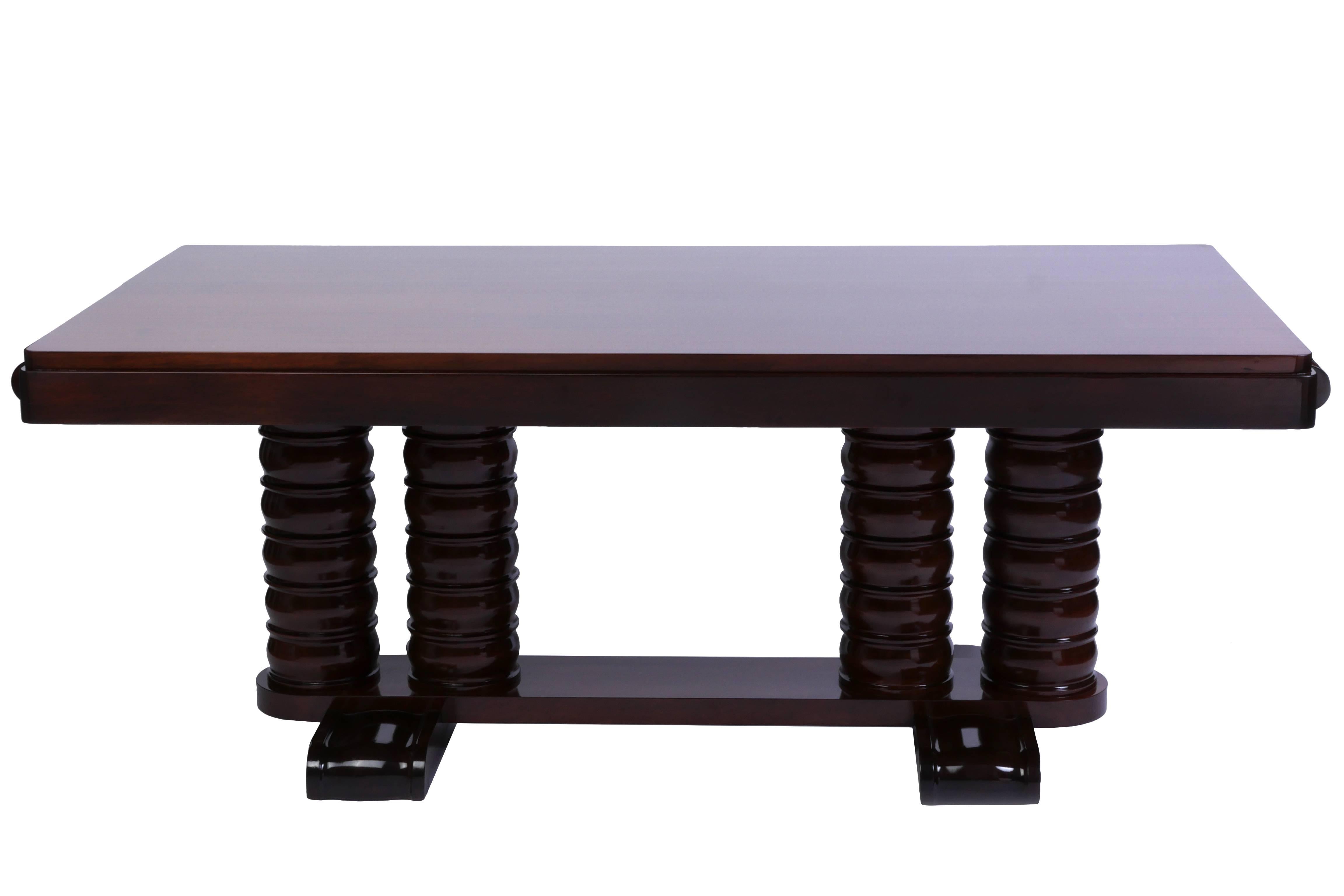 This exceptional 1940s French Art Deco solid mahogany dining table was designed and executed by Gaston Poisson and features exquisite straight lines and clean carved curve details on the legs, feet and extension rail ends. This table is a fantastic