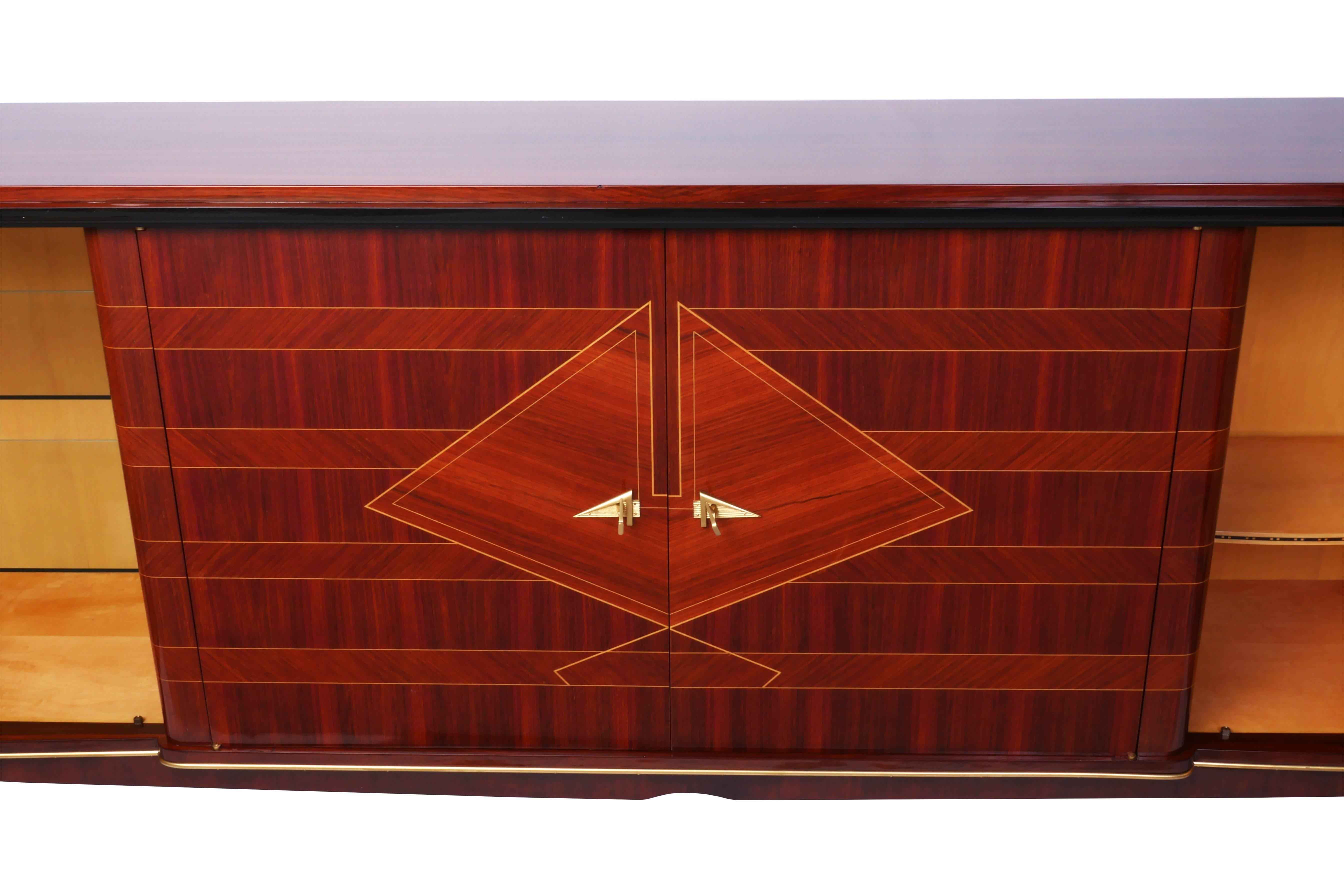 Wonderful French Art Deco buffet or sideboard in flame mahogany, with a gorgeous marquetry front with ivory inlay depicting a fan design. The piece features four doors concealing four glass shelves, four drawers with mirror fronts, and a bar area.