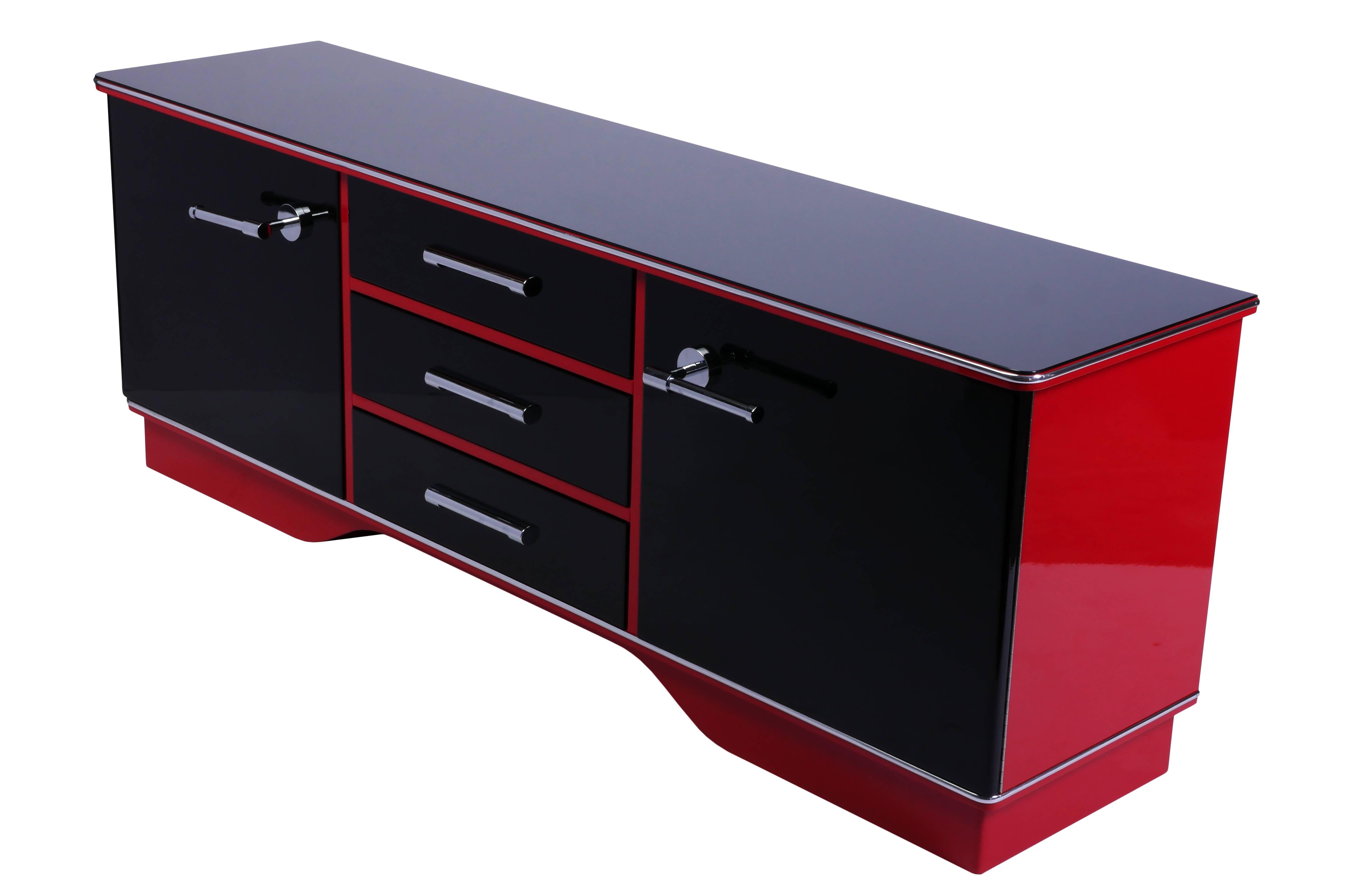This captivating Art Deco commode features a two-toned high gloss lacquer in black and cherry. It has two swing doors, three drawers and chrome detailing and fixtures.

Made in France, circa 1930.
   