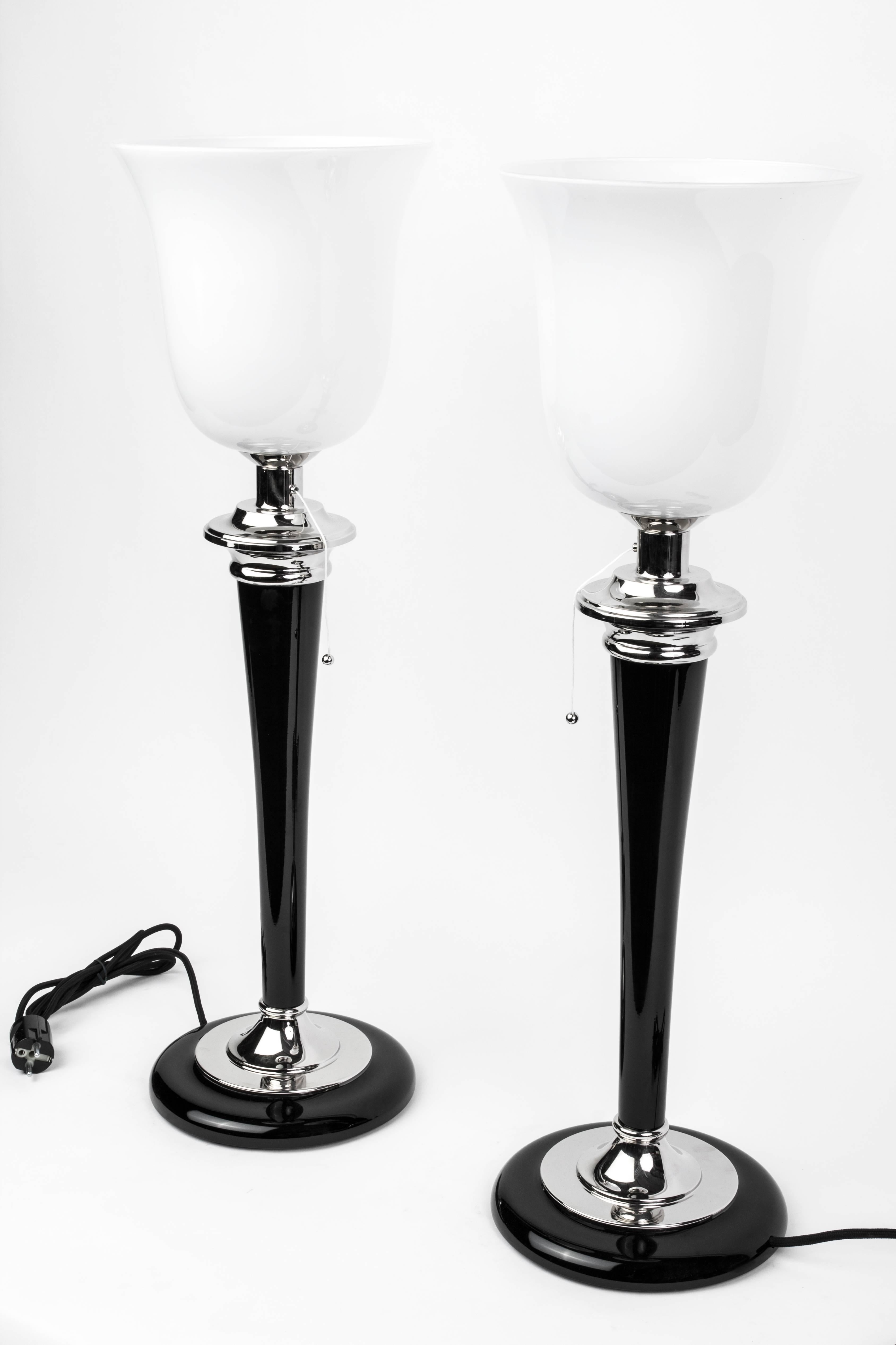 This beautiful pair of Art Deco style table lamps were designed by Mazda. They feature an opaque glass shade with chrome detailing, finished in a high gloss black lacquer.

Made in Germany modern.