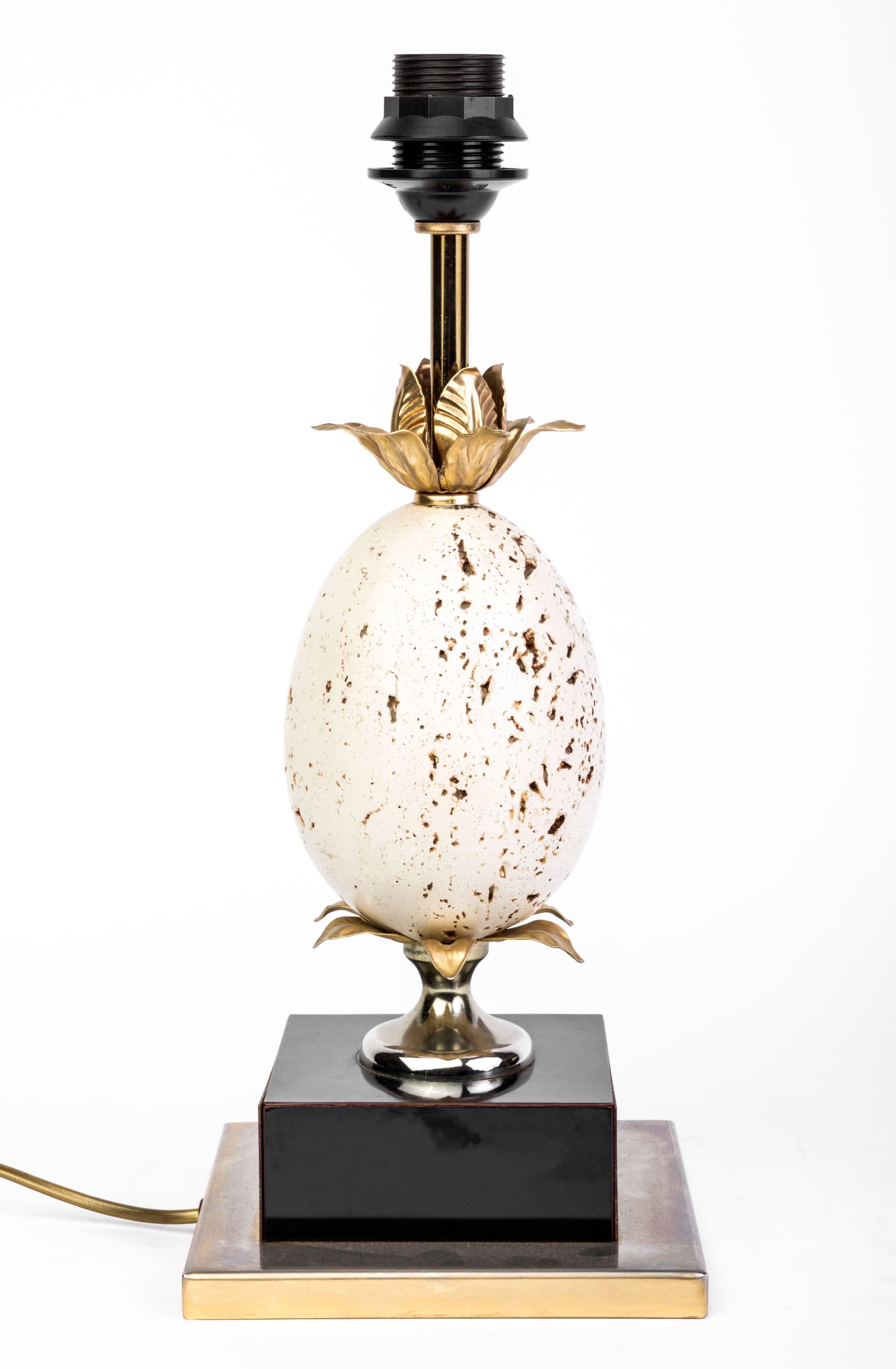 This stunning table lamp in the manner of Maison Charles Janssen features a gorgeous brass leaves design that holds a travertine ostrich egg. The lamp has been fitted with a very chic embossed black leather shade. 

Made in America, circa 1970.
