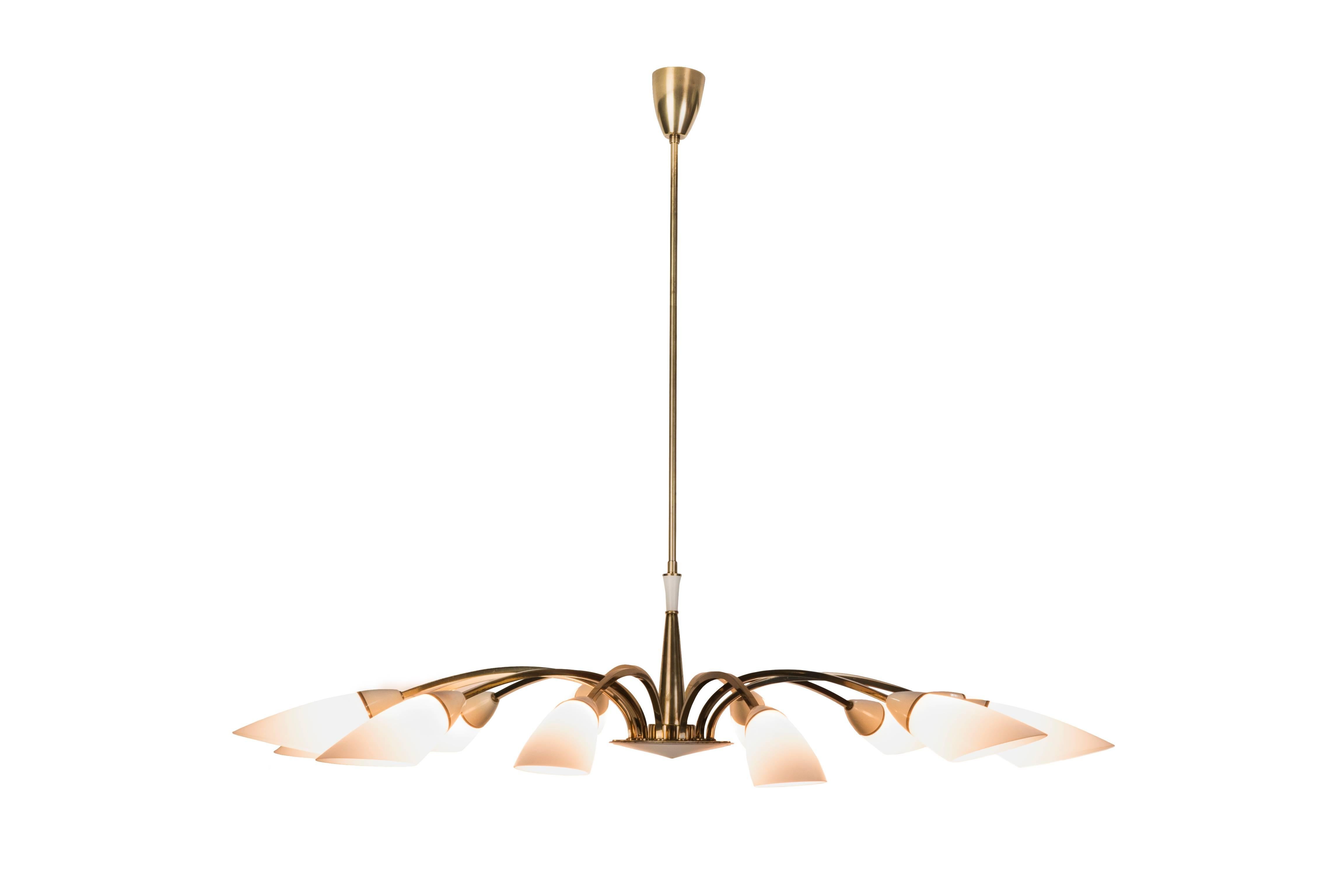 This gorgeous Italian 1950s chandelier was designed by Stilnovo. It features a spider form design brass frame with 12 double-layer blown opal glass shade and white enamel centrepiece.

Made in Italy, circa 1950.