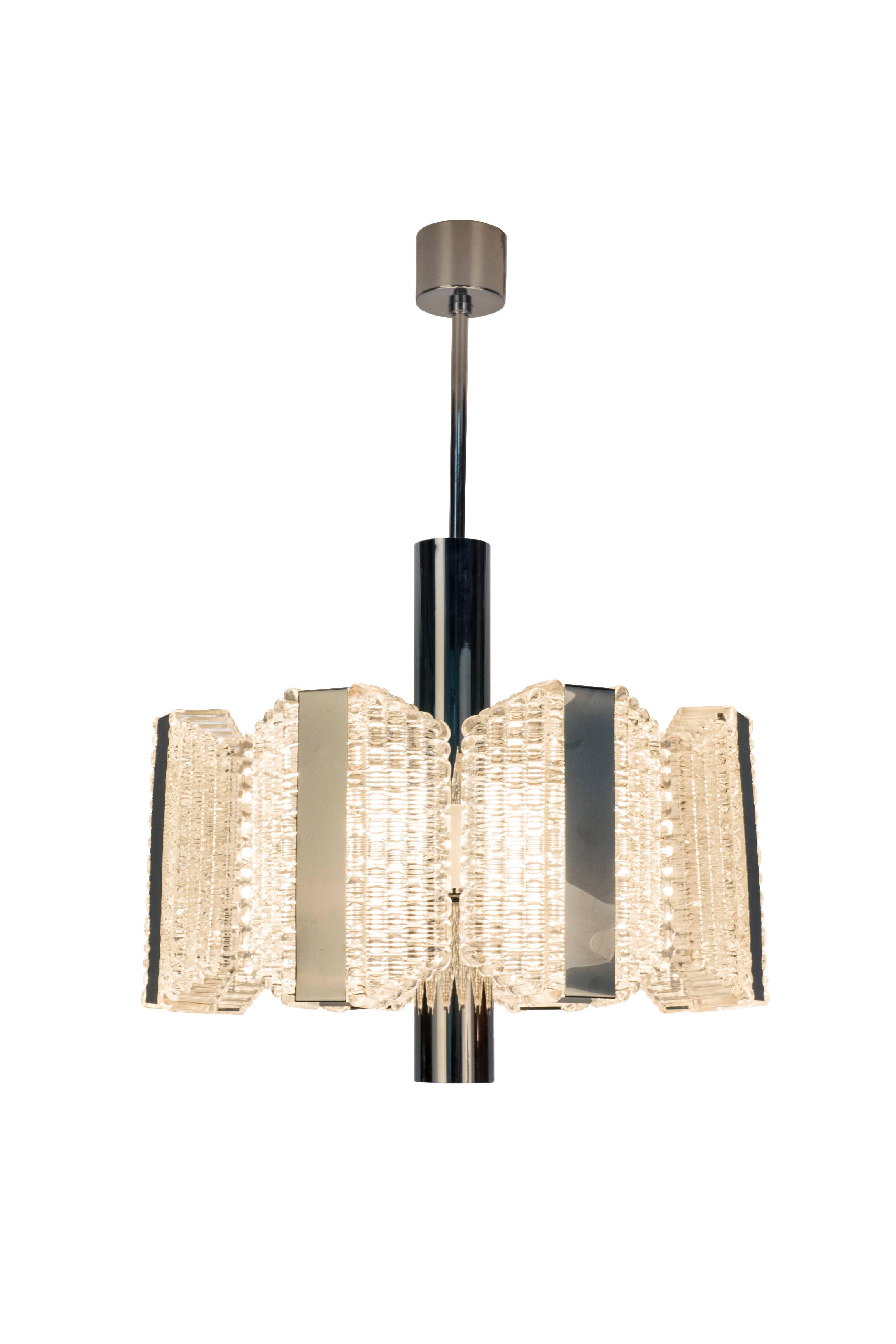 This sensational Grand Skyscraper Mid-Century Modernist chandelier was designed by Kaiser Leuchten. It features an octagonal shape, textured relief glass design and chrome banding detail. It has been completely rewired and is in excellent