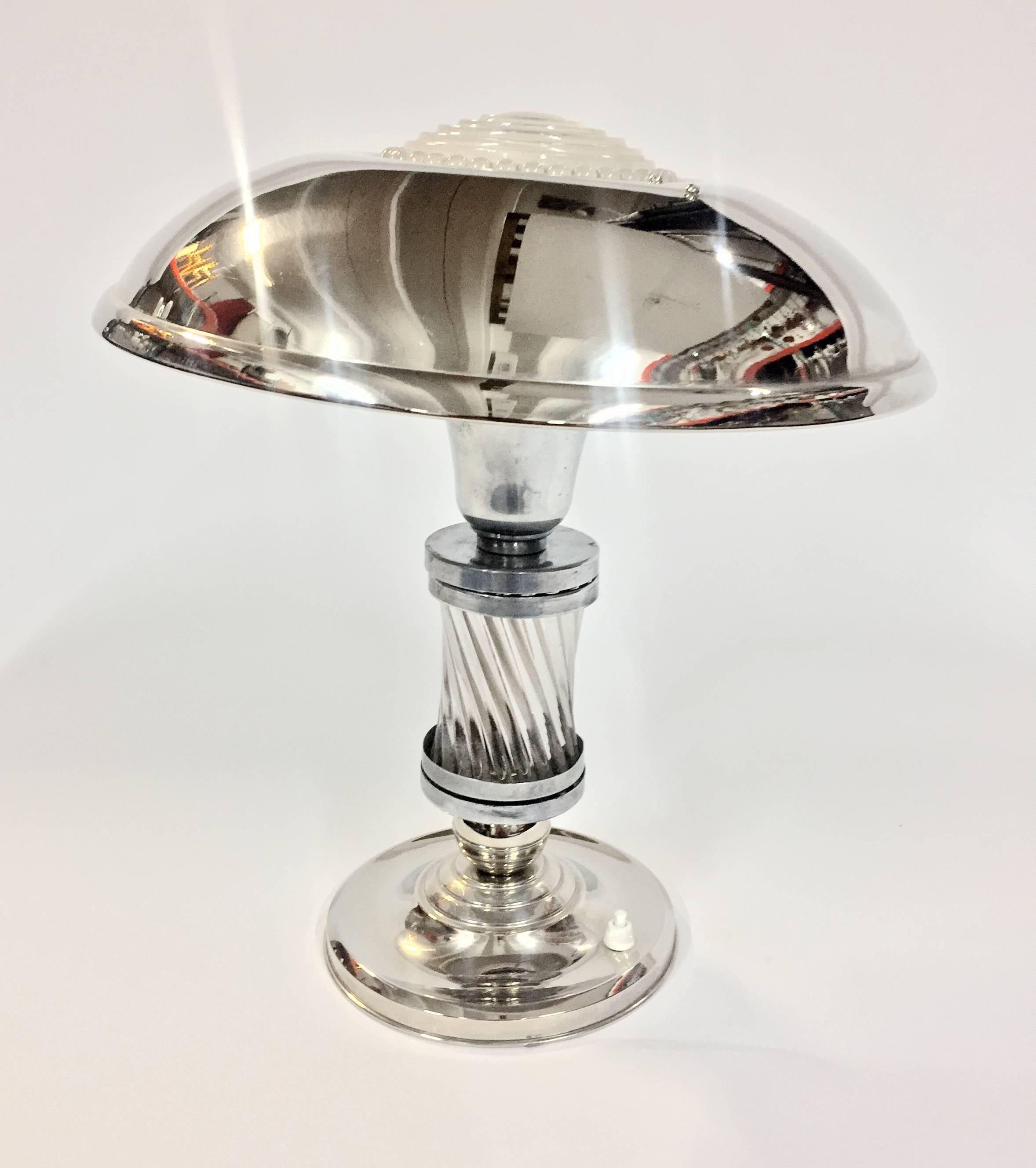 This luxe Art Deco table lamp, circa 1925 features a chrome-plated body with a silvered base and shade for a gorgeous contrast. Glass rods on the body and molded glass plate to top the shade. The shade swivels for convenience. Iconic Art Deco design