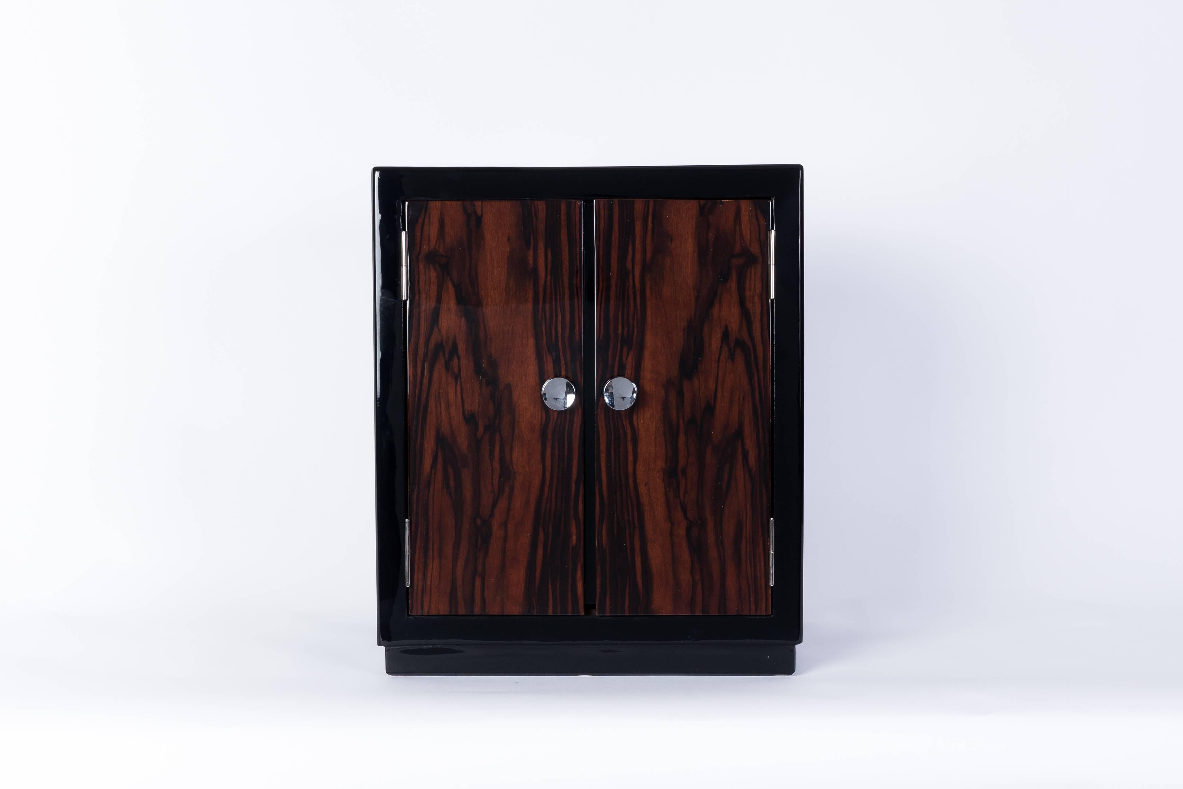 This captivating French Art Deco petit bar cabinet features two frontal swing doors in Macassar and chrome handles and fixtures. Interior in matte black with an adjustable shelf.