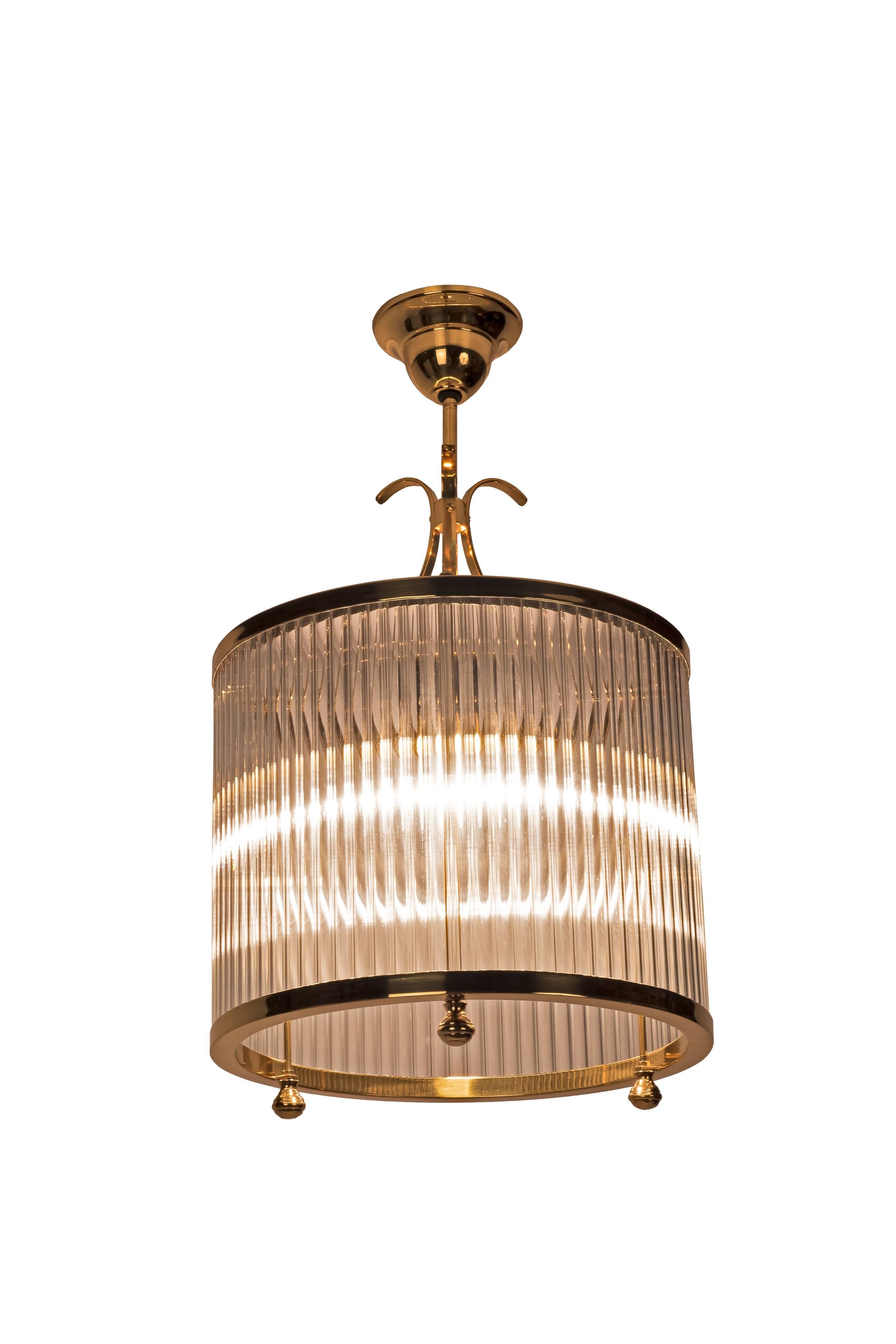 This Luxe cylindrical Art Deco chandelier in the style of Petitot features a polished brass frame with tubular glass inserts. Brass has been newly polished and piece rewired to American standards.
