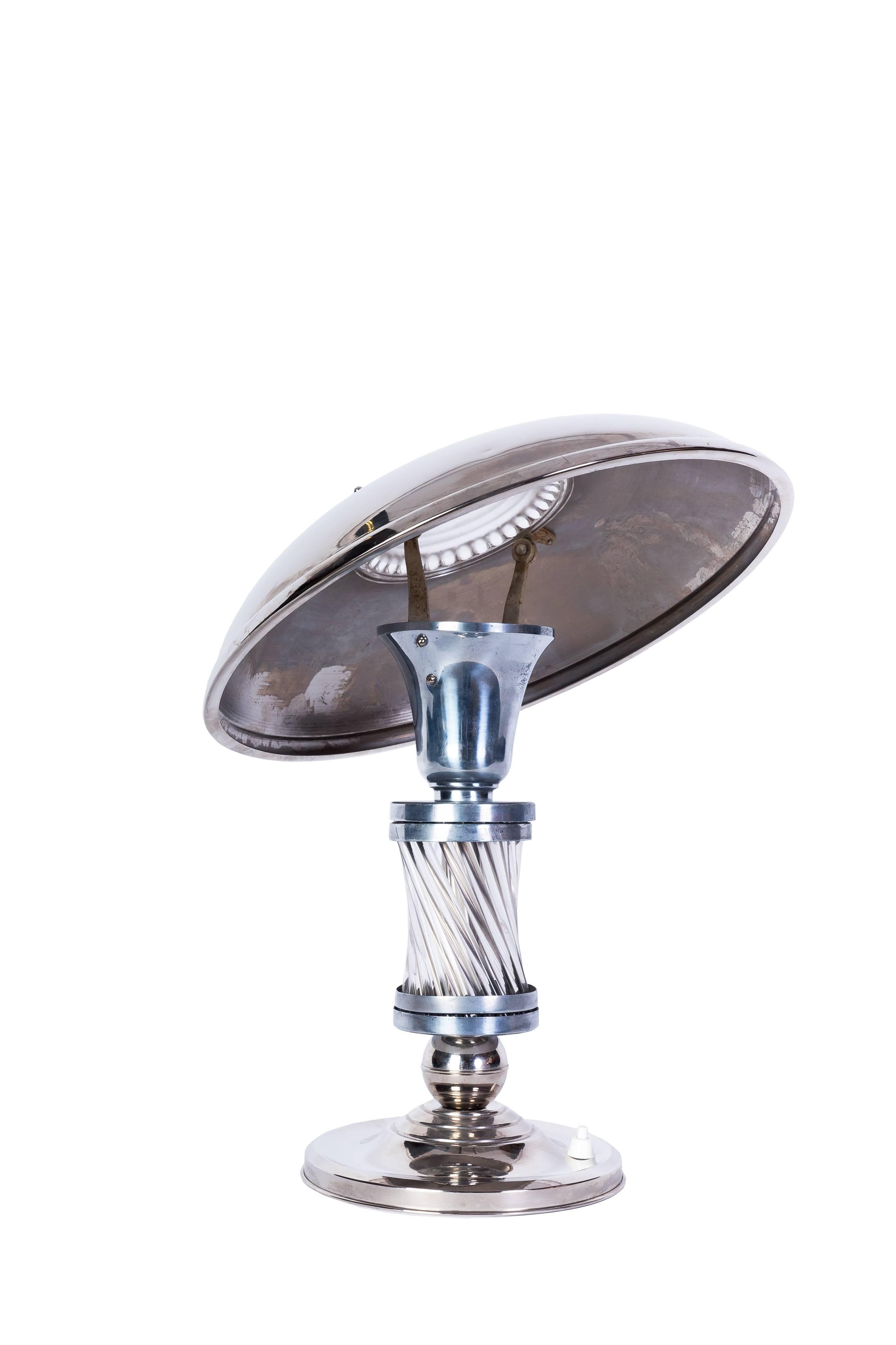 Cette luxueuse lampe de table Art déco (vers 1925) présente un corps chromé avec une base et un abat-jour argentés pour un contraste magnifique. Tiges de verre sur le corps et plaque de verre moulé pour coiffer l'abat-jour. L'abat-jour pivote pour
