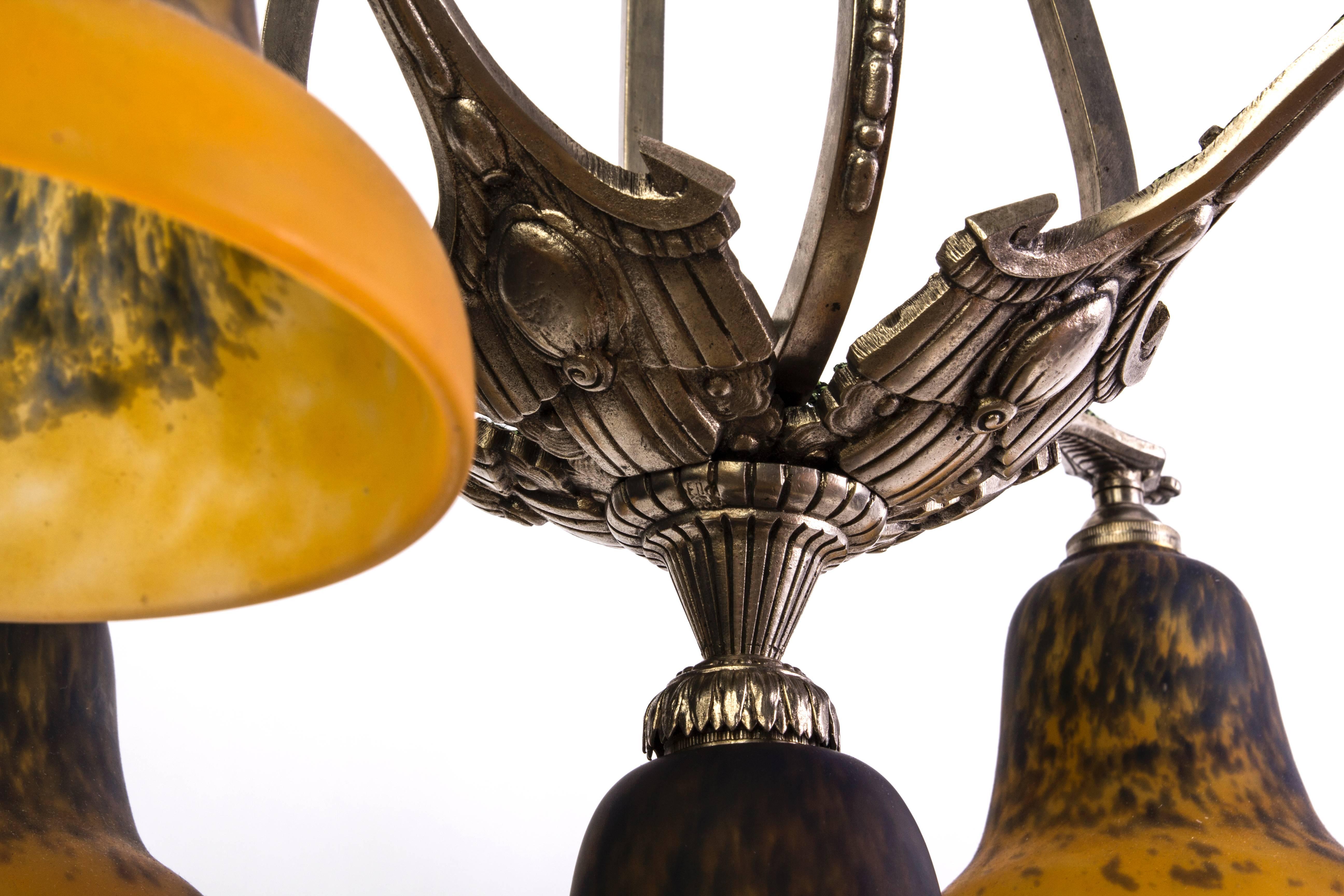 Dieser beeindruckende französische Art-déco-Kronleuchter wurde von Charles Schneider entworfen. Sie verfügt über einen vernickelten Bronzerahmen mit floralen Ornamenten und fünf (5) Glasschirmen in den Farben Perle, Moos und Mandarine.