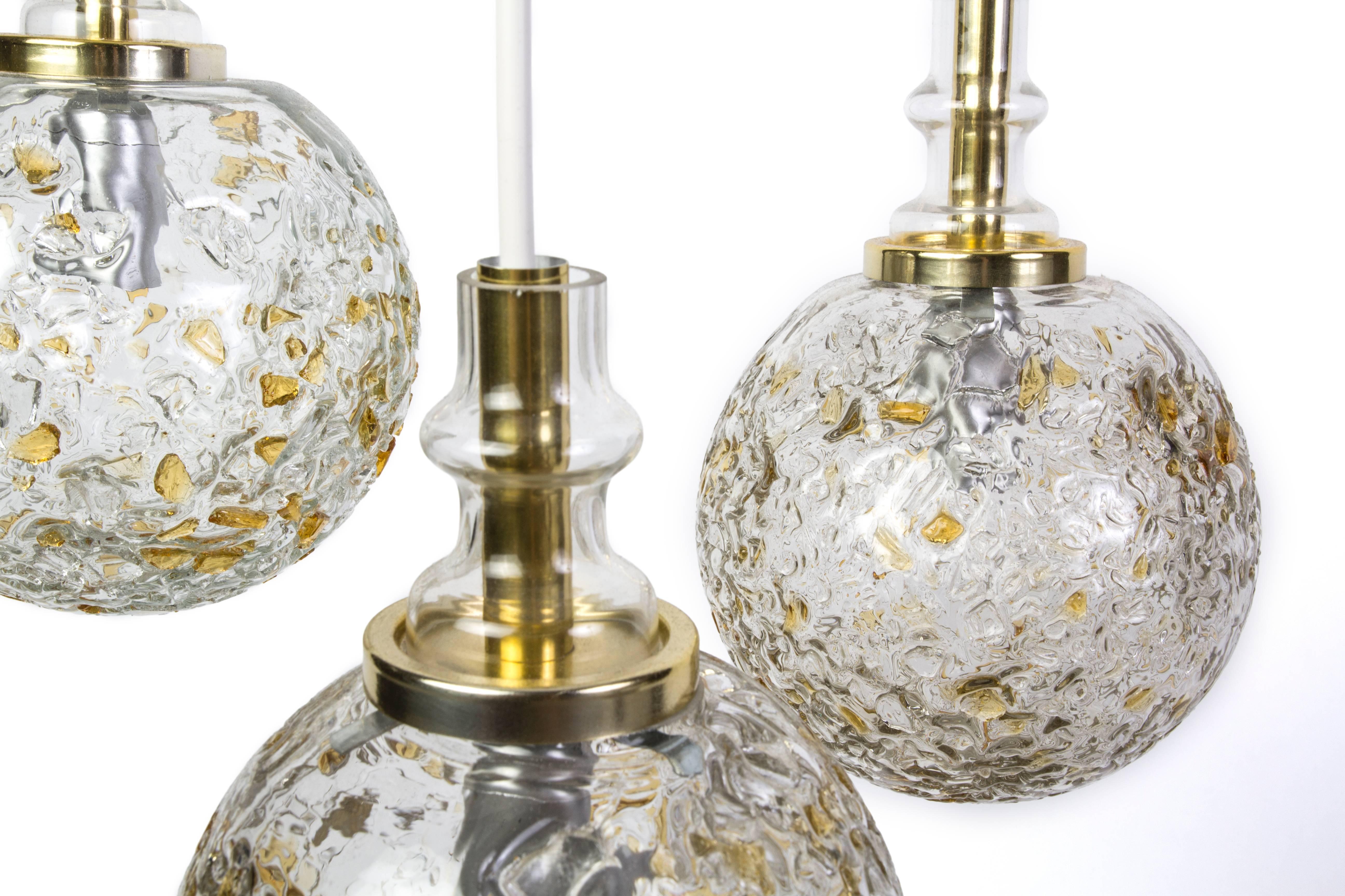 This exquisite 1960s Mid-Century Modernist chandelier was designed by Doria. It features a pendant design with three handblown etched gloss globes with hues of gold and sand.
                   