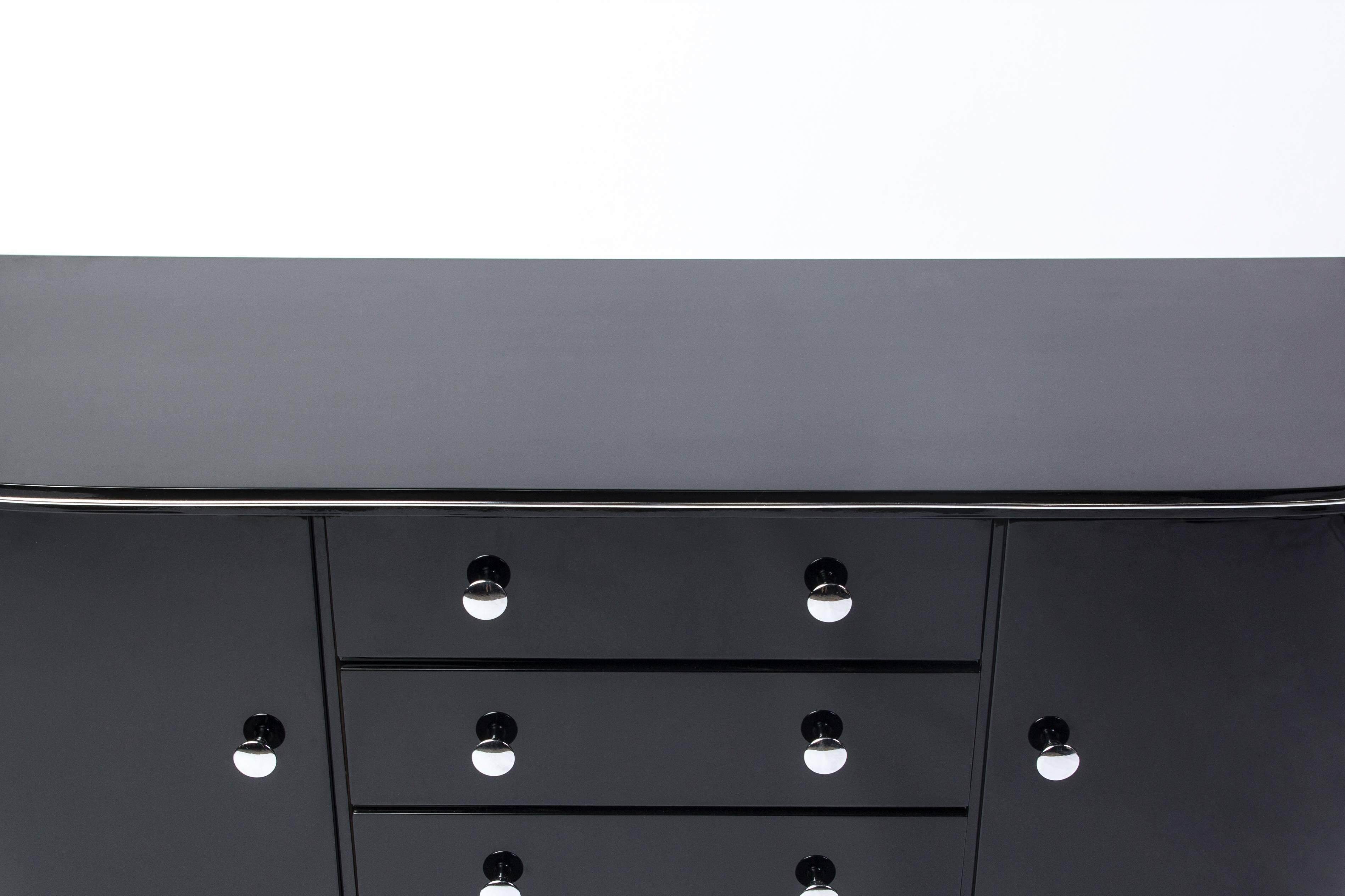 This wonderful Art Deco low board / chest features a curved round design with two swing doors, chrome detailing and fittings, finished in a high gloss black lacquer.