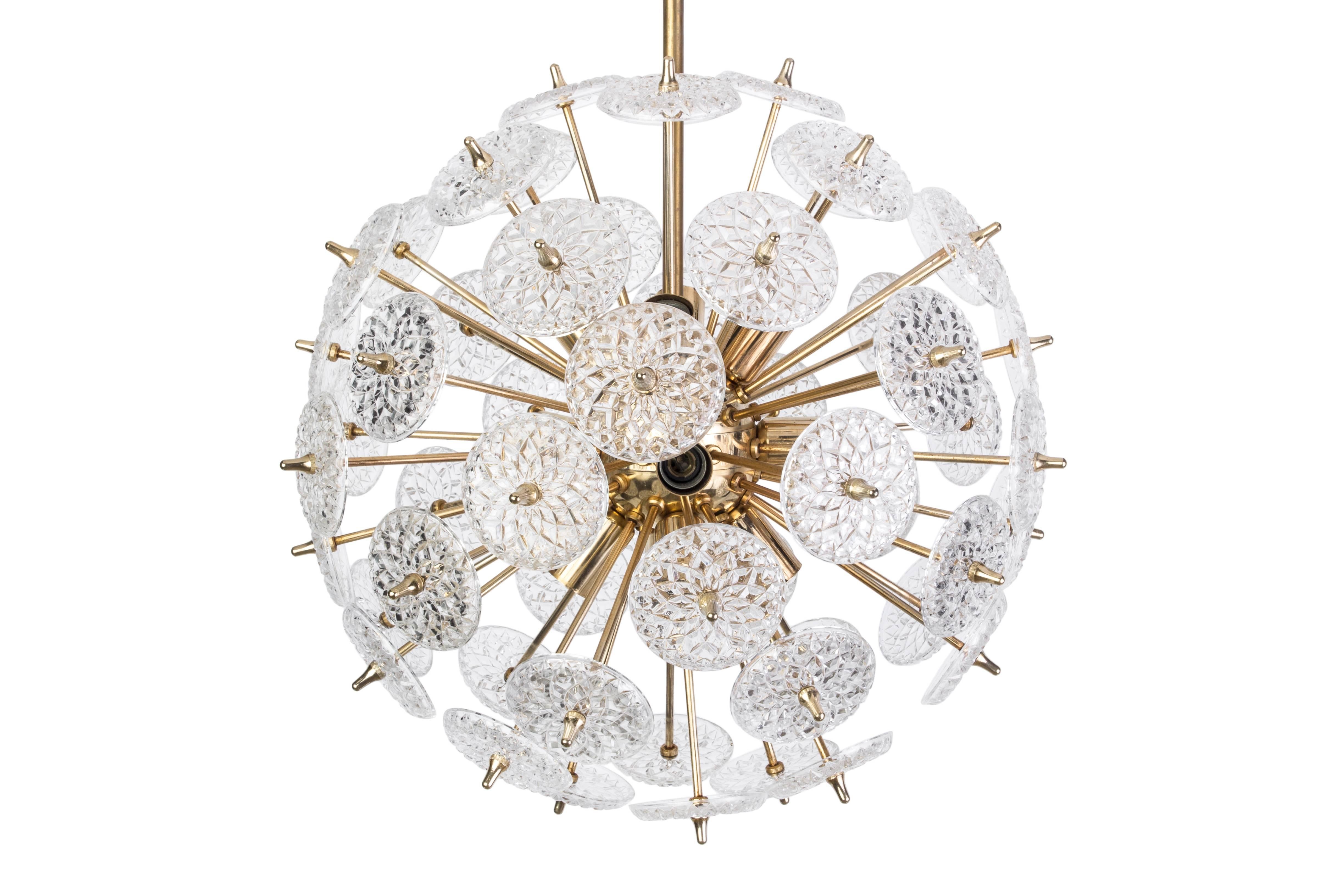 This exquisite Mid-Century Modernist floral Sputnik was created by the prolific Val Saint Lambert. It features twelve lights, on a starburst design form in brass with stylized floral cut crystal discs surrounding the base. It has been newly rewired