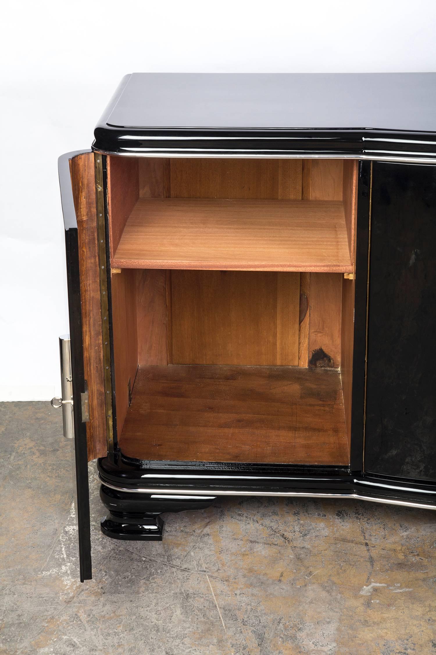 This elegant streamlined Art Deco sideboard features a beautiful curved center and two swing doors to reveal plenty of storage. The piece has been finish in black lacquer with chromed line detailing and hardware.
Measures:
69 1/2” W x 23” D, 27