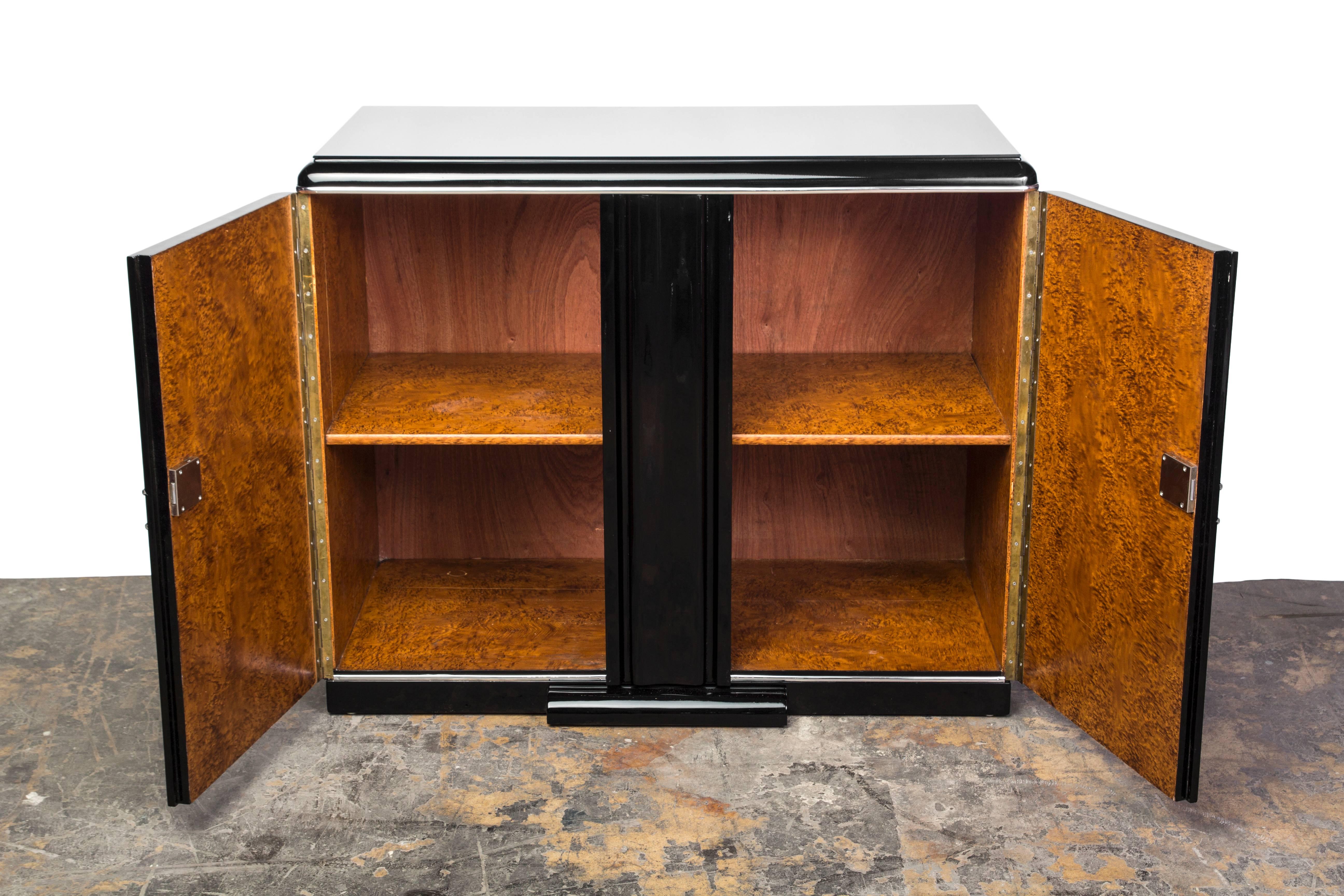 This impressive Art Deco commode features swing doors with chrome detailing and finished in a high gloss black lacquer. Interior in burl (Loupe d’Amboine).