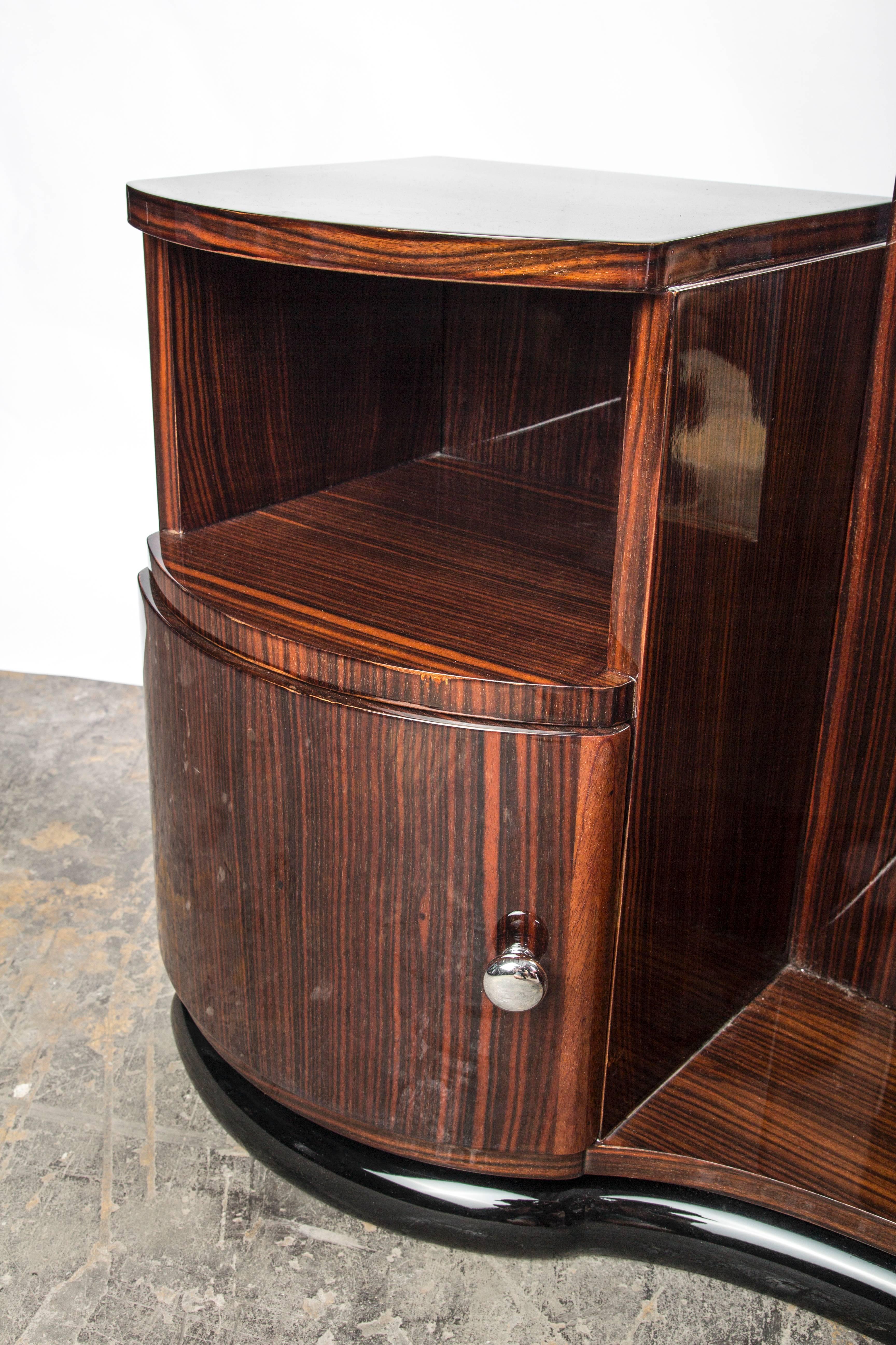 Ce magnifique meuble-lavabo/commode Art déco présente du bois de Macassar ronceux en finition brillante, avec des accents chromés et un miroir au centre.