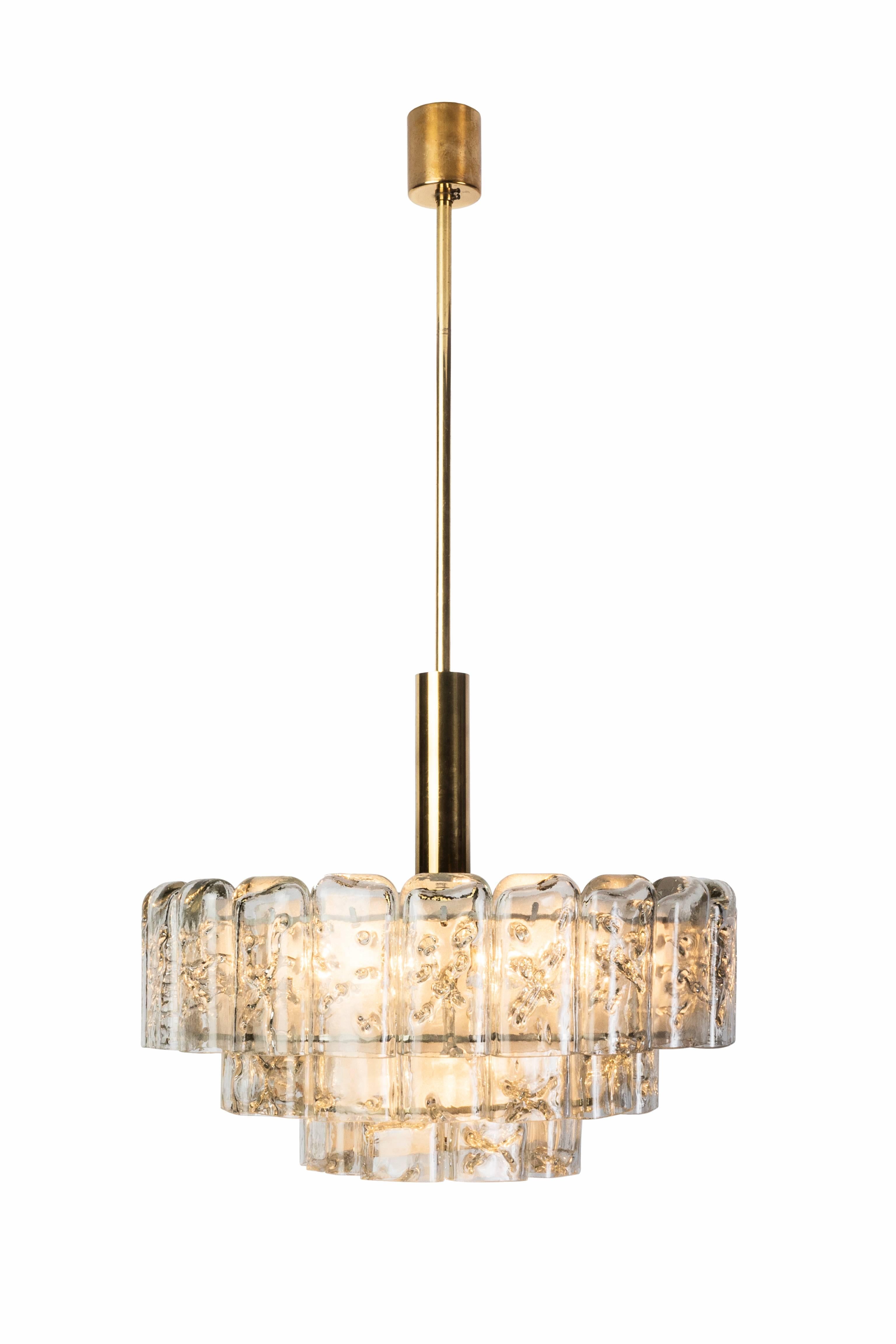 This gorgeous Mid-Century Modernist chandelier by Doria. It features a brass circular frame cascading into (three) tiers of textured bubble glass accents.
 

