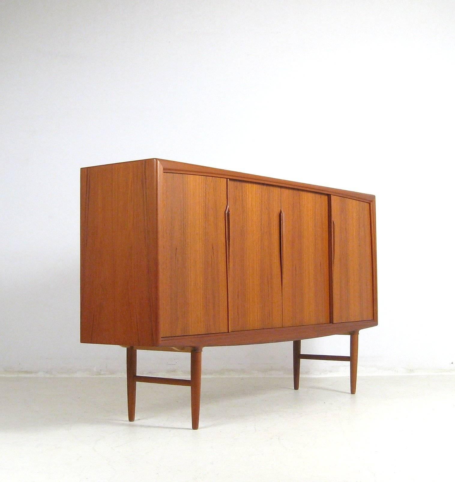 Large teak sideboard/credenza from the 1960s.

Typically Danish, this is not only a wonderful looking unit it has a large amount of storage too. Function and style!

Four large sliding doors fitted with beautiful curled-back handles reveal