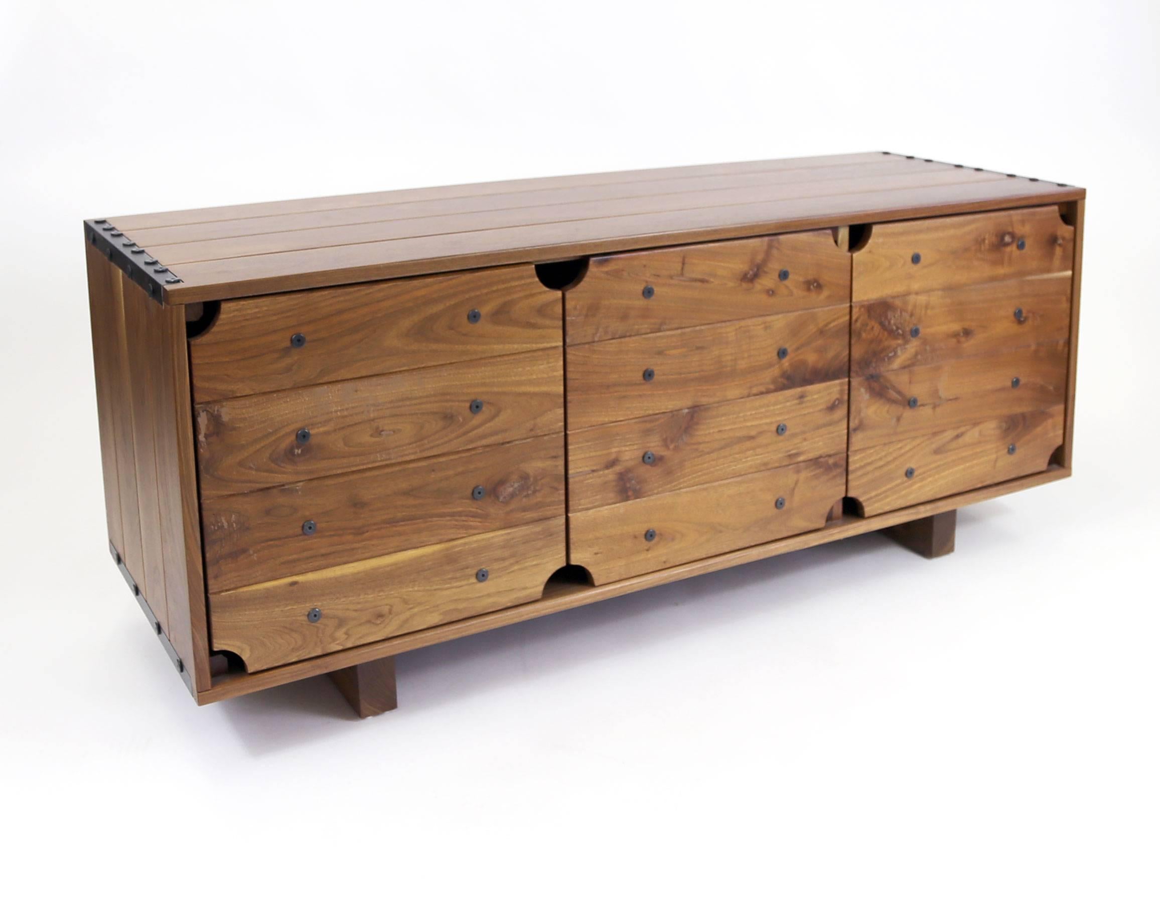 A simple credenza that hearkens back to an earlier time. Wooden battens (here, using black walnut) secured with steel braces and bolts hold everything together. The boards are eased with a slight gap between that compliments the primitive look of